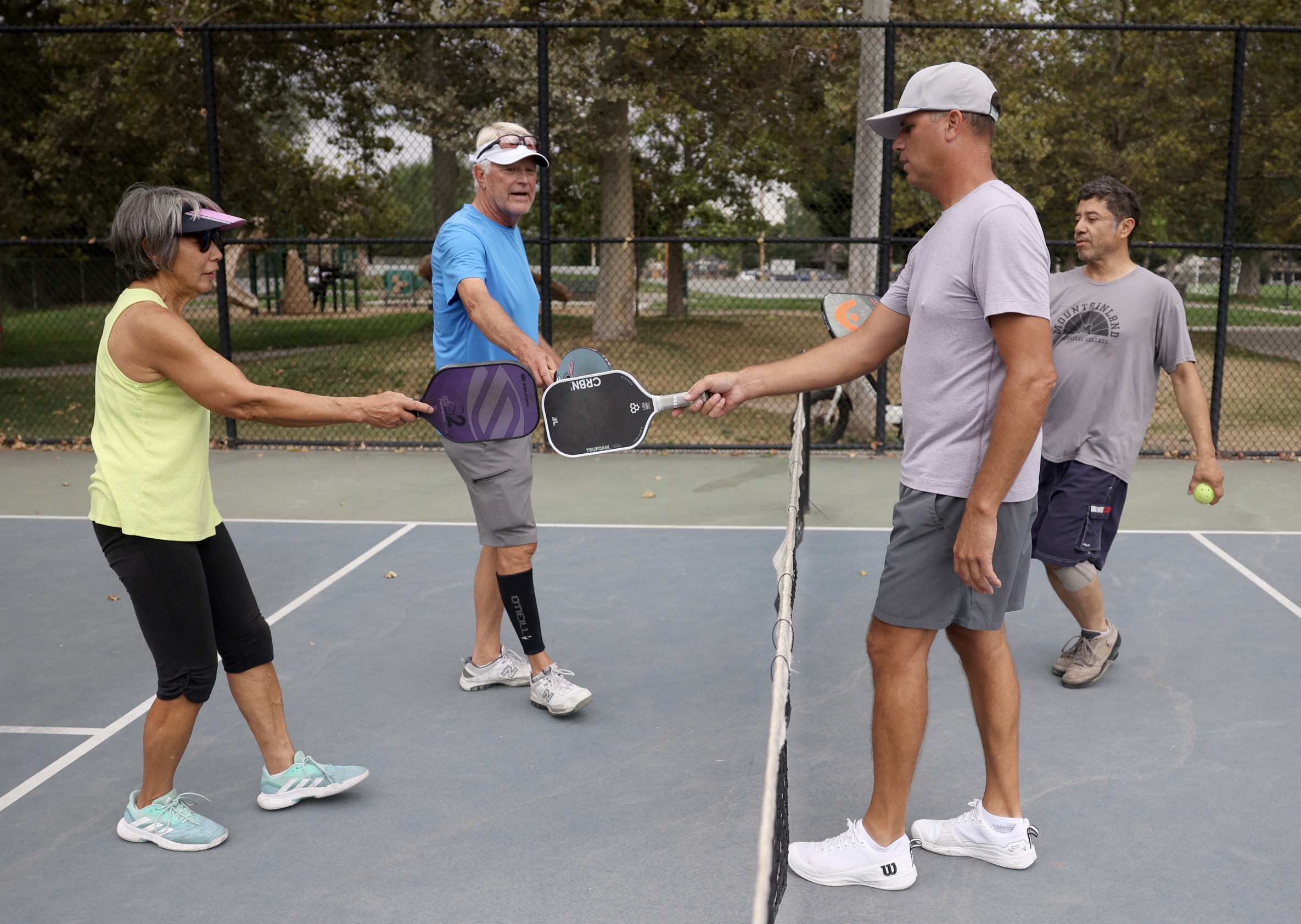 Brenda Koga, Lon Stalsberg, Chad Oberson and Johnny Garcia tap paddles after playing pickleball at Fairmont Park in Salt Lake City on Aug. 26.