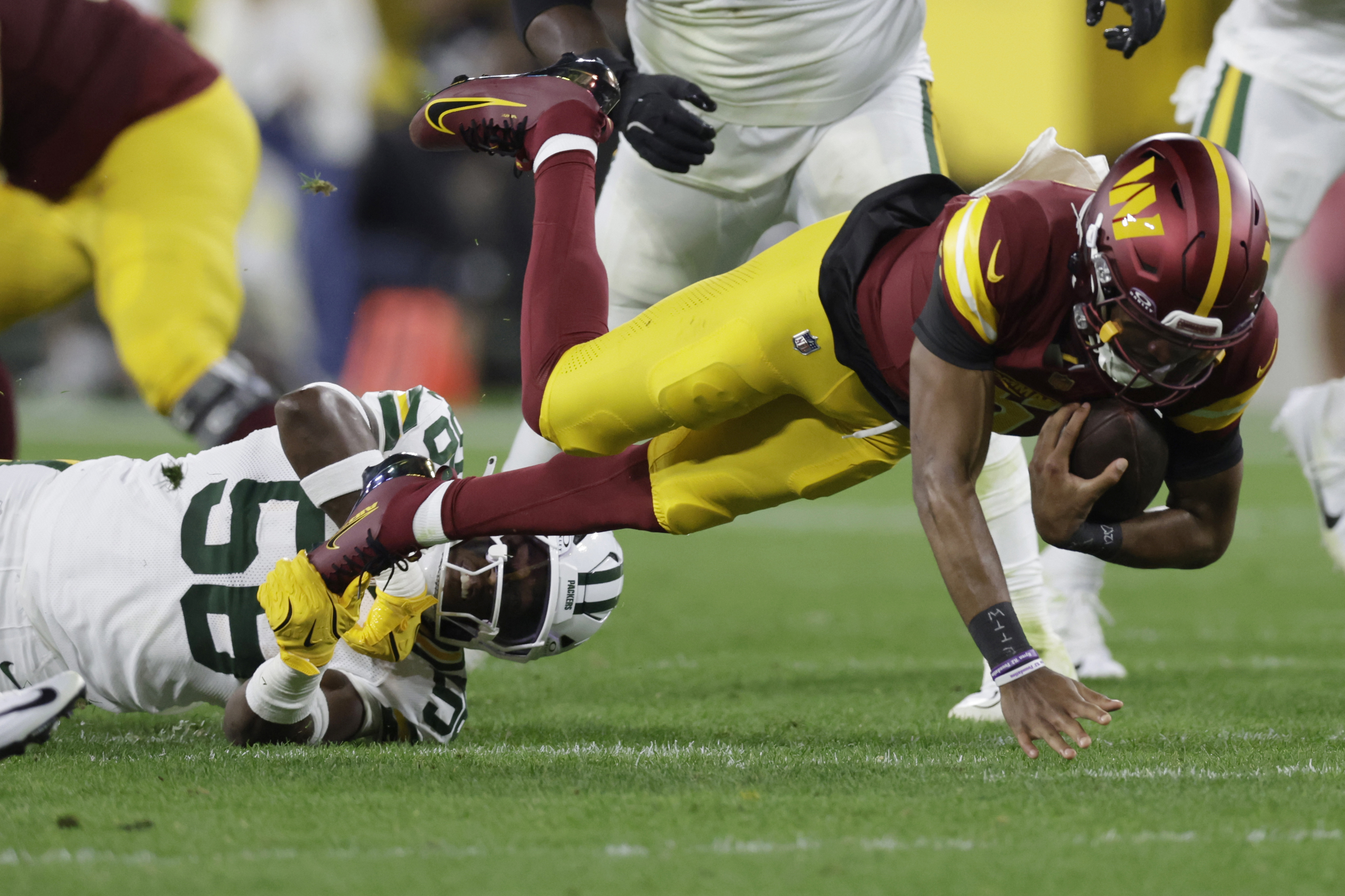Washington Commanders quarterback Jayden Daniels, right, struggles for yardage as Green Bay Packers linebacker Isaiah McDuffie (58) defends during the first half of an NFL football game Thursday, Sept. 11, 2025, in Green Bay, Wis.