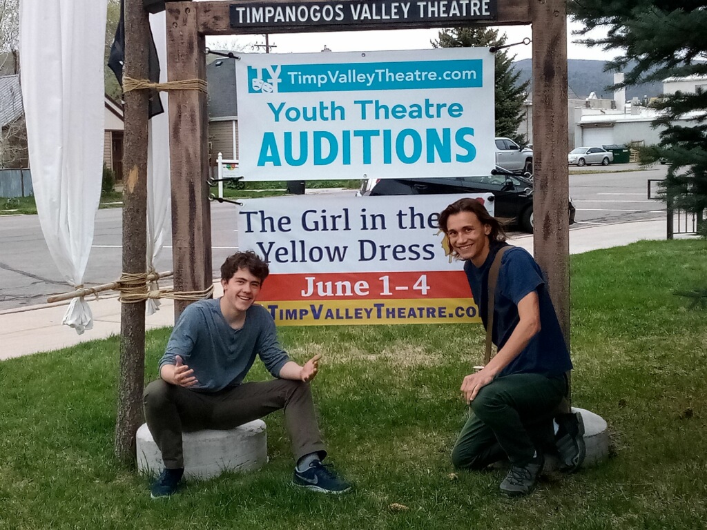 Tal Hughes and Ethan Scott pose near a sign advertising their original play "The Girl in the Yellow Dress" in Heber City in June 2022.