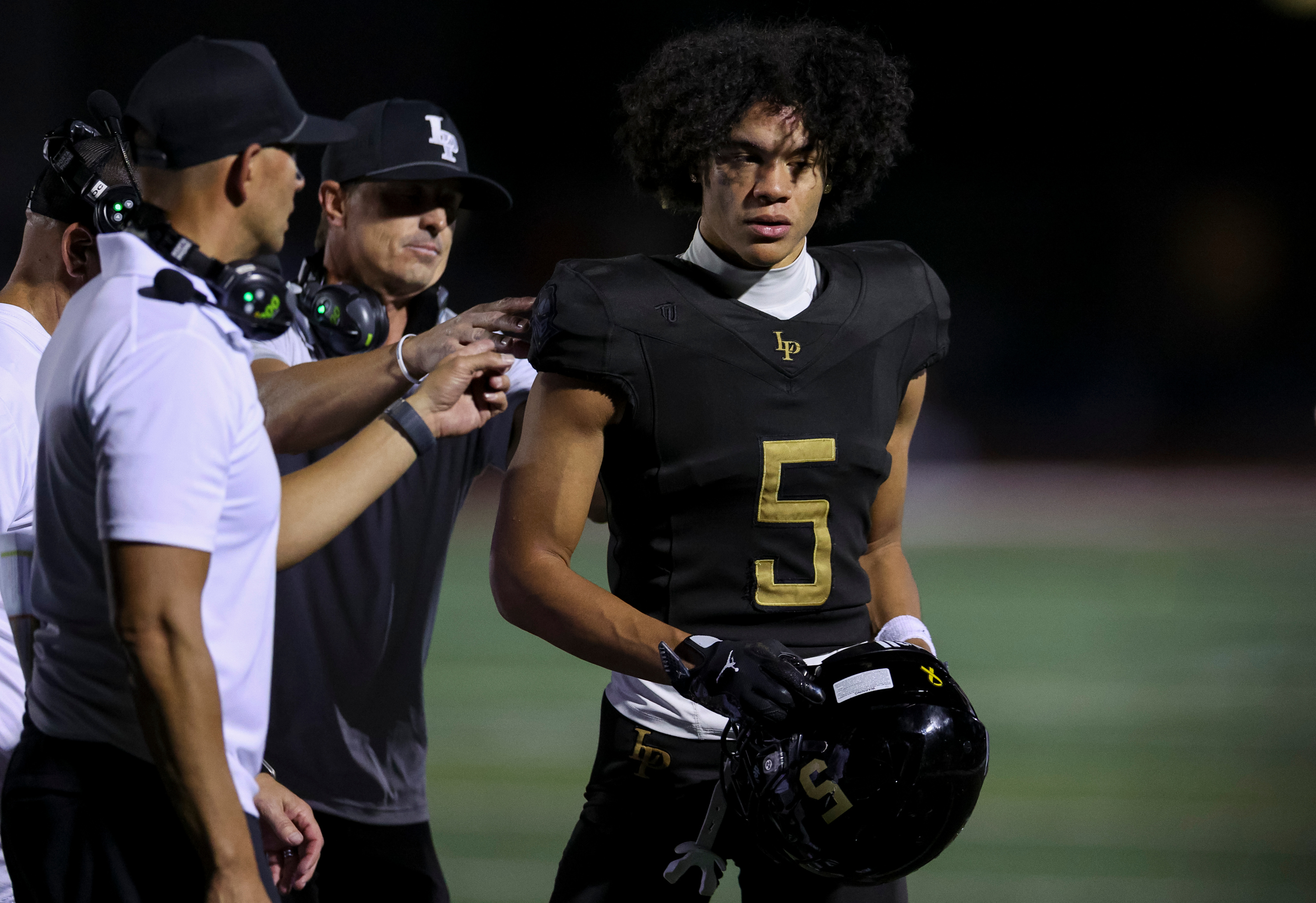 Lone Peak's Jaron Pula (5) speaks with his coaches as Lone Peak plays Corner Canyon in a football game at Lone Peak High School in Highland on Friday, Sept. 19, 2025.