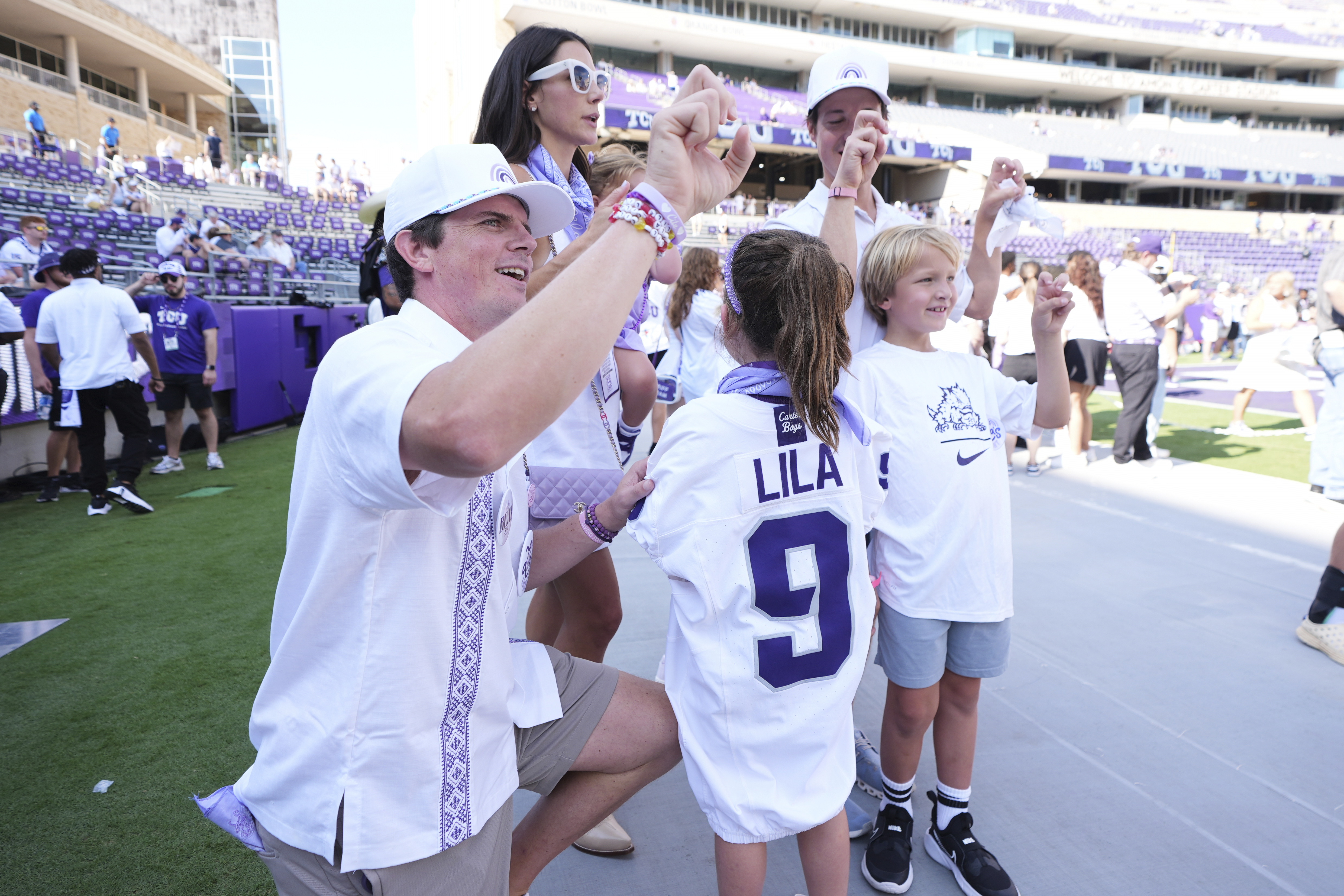 Blake Bonner, left, his wife Caitlin, left rear, standing and their daughter, front, wearing a shirt with her late sisters name stand in the end zone before an NCAA college football game between SMU and TCU, Saturday, Sept. 20, 2025, in Fort Worth, Texas. 