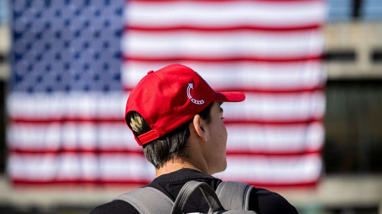 Ryker White, a freshman at Utah Valley University, wears a hat with the Turning Point USA logo on it as he talks with a friend near an American flag displayed in the courtyard on the campus of UVU in Orem on Wednesday.