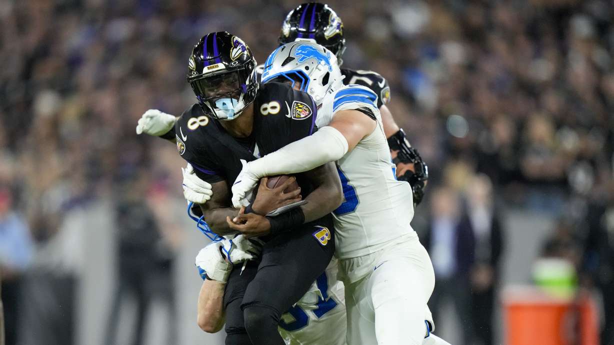 Baltimore Ravens quarterback Lamar Jackson (8) is brought down by Detroit Lions linebacker Trevor Nowaske, right, and defensive end Aidan Hutchinson, bottom, during the second half of an NFL football game Monday, Sept. 22, 2025, in Baltimore.