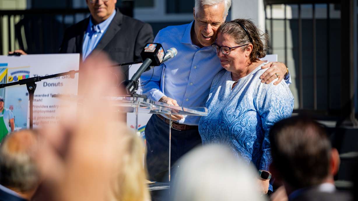 Joseph Grenny, co-founder of the Other Side Village, left, hugs villager Lori McQueen, right, at a press conference celebrating the Other Side Village Phase 2 expansion after securing $30 million in donations to overcome chronic homelessness Tuesday.