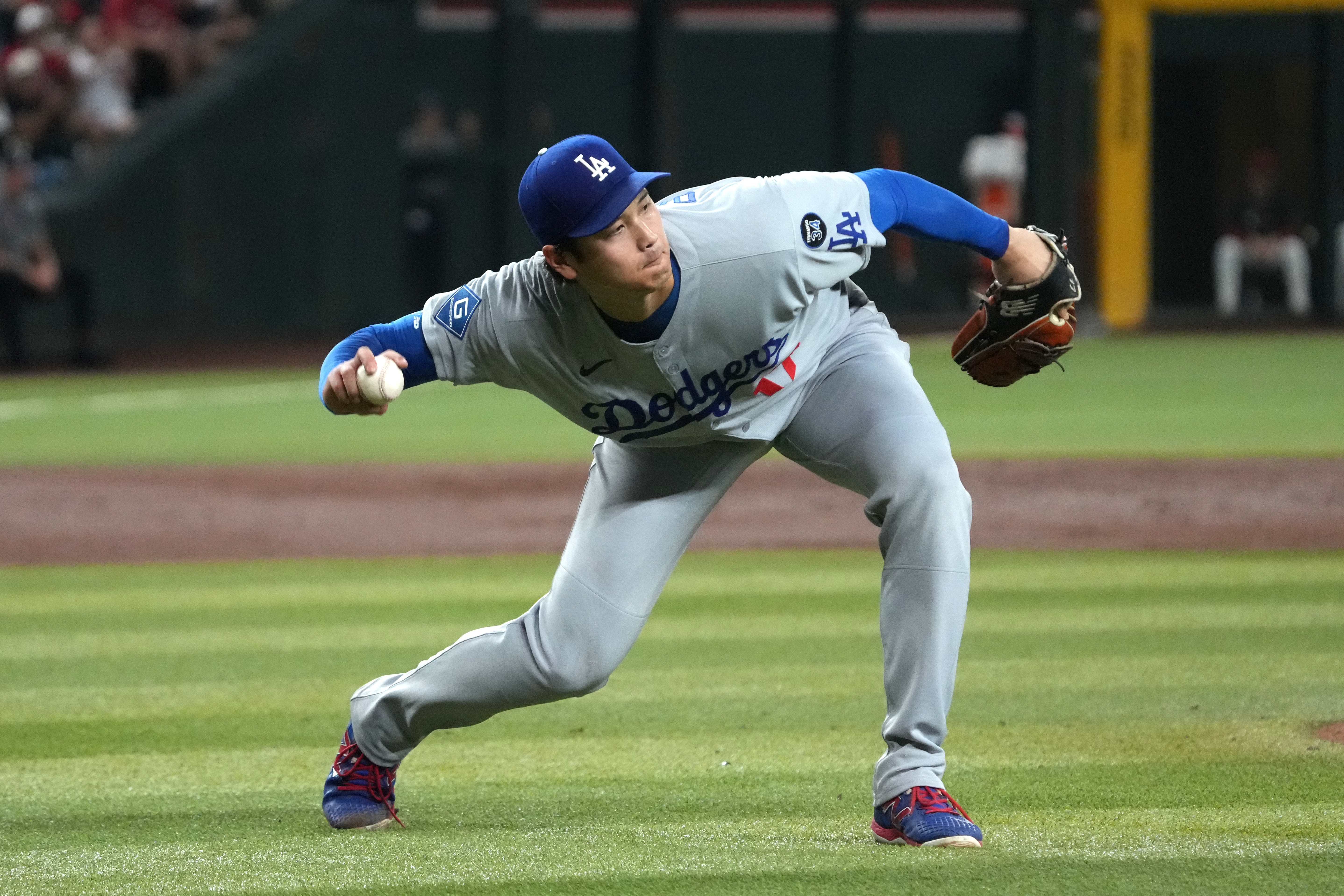 Los Angeles Dodgers pitcher Shohei Ohtani fields the ball hit by Arizona Diamondbacks' Alek Thomas in the third inning of a baseball game, Tuesday, Sept. 23, 2025, in Phoenix. 