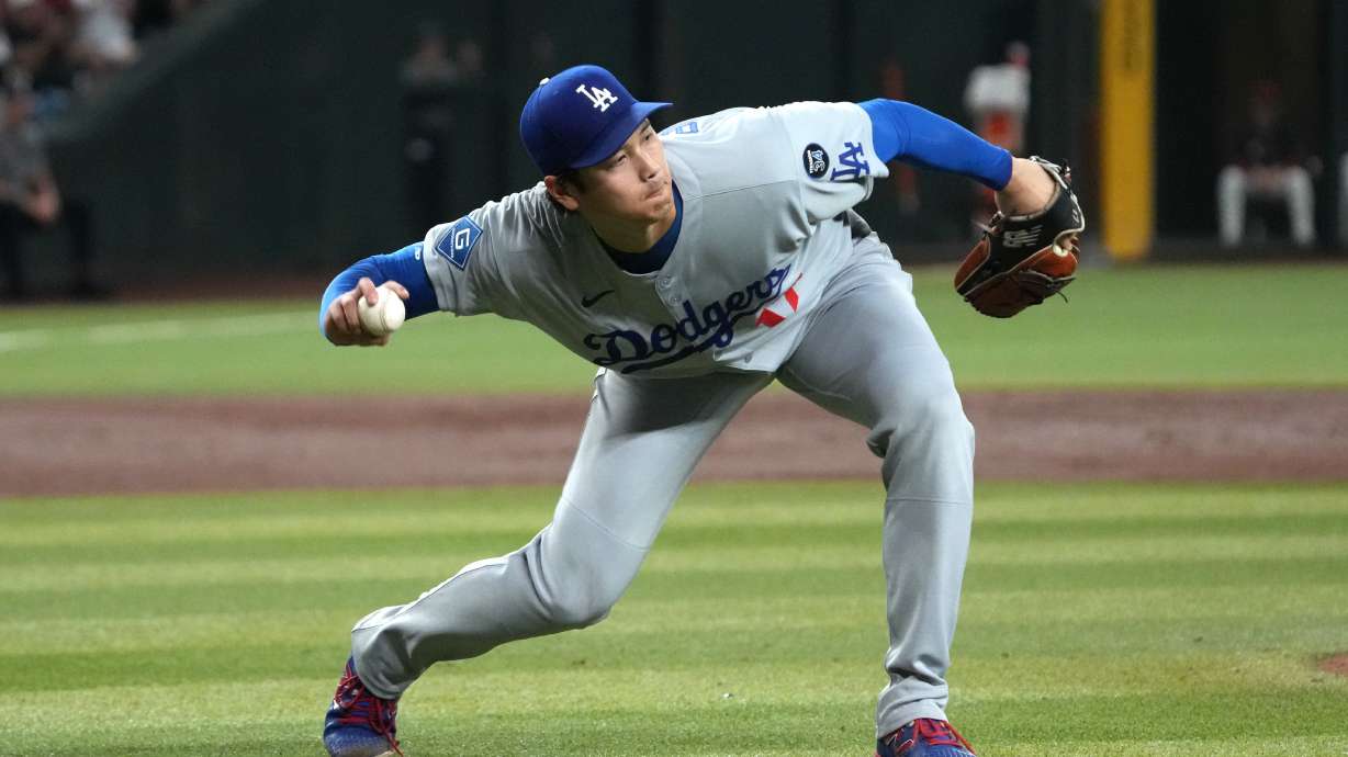 Los Angeles Dodgers pitcher Shohei Ohtani fields the ball hit by Arizona Diamondbacks' Alek Thomas in the third inning of a baseball game, Tuesday, Sept. 23, 2025, in Phoenix.