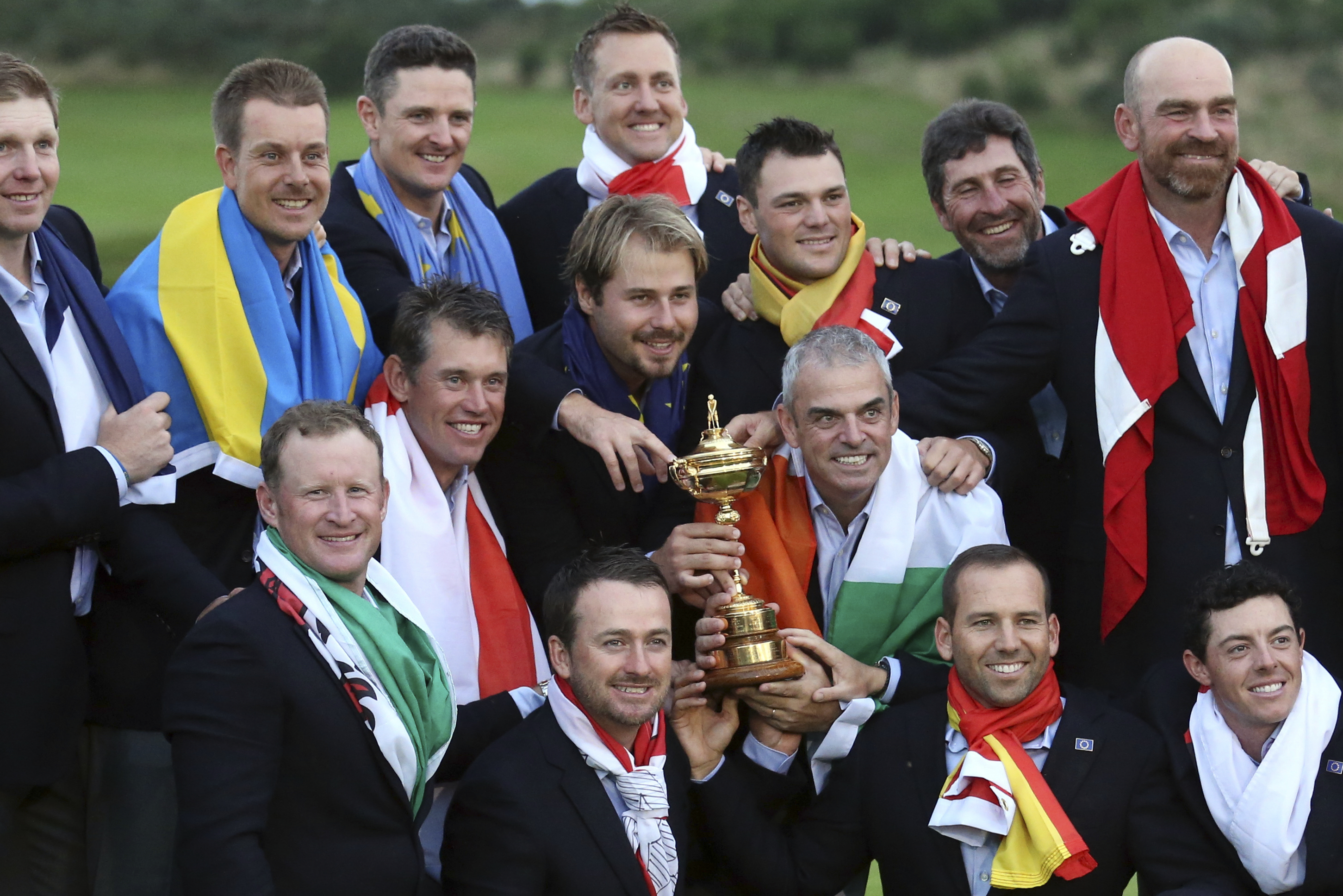 FILE - Europe team captain Paul McGinley, center right, and his team wear their national flags and celebrate with the trophy after winning the Ryder Cup golf tournament at Gleneagles, Scotland, Sunday, Sept. 28, 2014. 