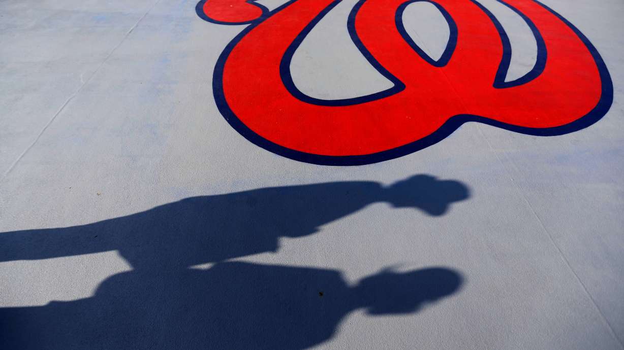 FILE - Fans cast shadows past a Washington Nationals logo as they walk in to Space Coast Stadium for an exhibition spring training baseball game between the Nationals and the New York Mets, Thursday, March 5, 2015, in Viera, Fla.