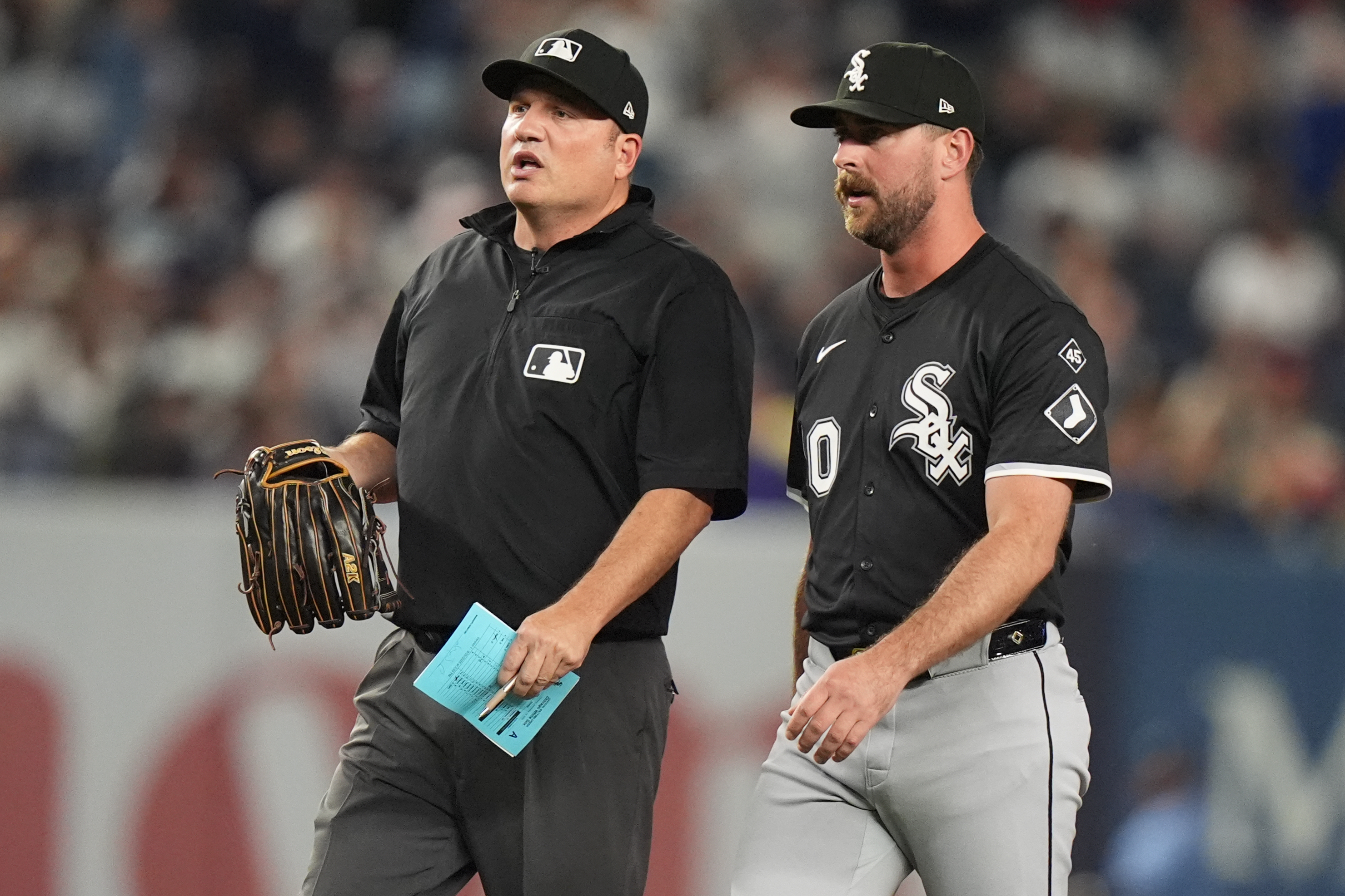 Umpire Dan Bellino holds the glove of Chicago White Sox pitcher Tyler Gilbert before he pitches during the fifth inning of a baseball game against the New York Yankees Thursday, Sept. 25, 2025, in New York. 