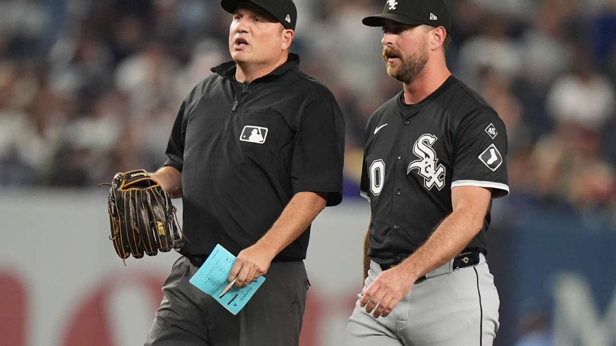 Umpire Dan Bellino holds the glove of Chicago White Sox pitcher Tyler Gilbert before he pitches during the fifth inning of a baseball game against the New York Yankees Thursday, Sept. 25, 2025, in New York.