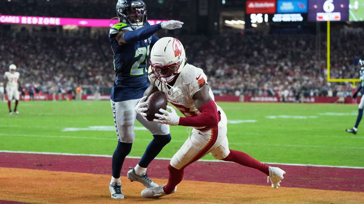 Arizona Cardinals wide receiver Marvin Harrison Jr., right, catches a touchdown pass as Seattle Seahawks cornerback Devon Witherspoon defends during the second half of an NFL football game Thursday, Sept. 25, 2025, in Glendale, Ariz.