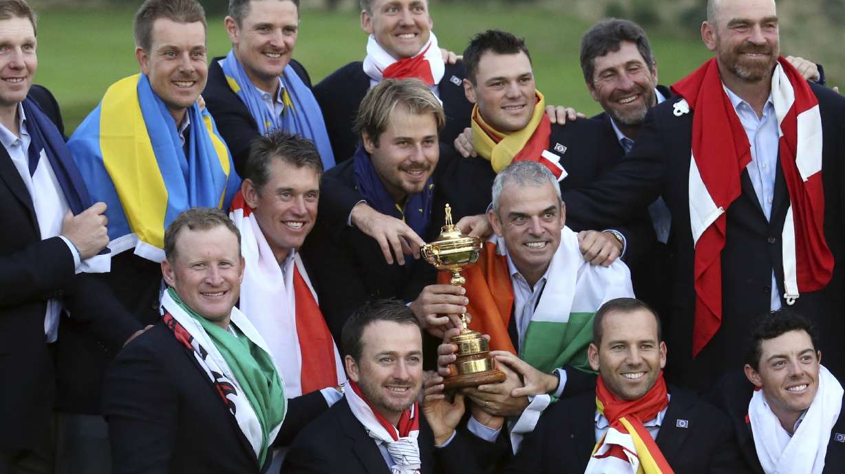 FILE - Europe team captain Paul McGinley, center right, and his team wear their national flags and celebrate with the trophy after winning the Ryder Cup golf tournament at Gleneagles, Scotland, Sunday, Sept. 28, 2014.