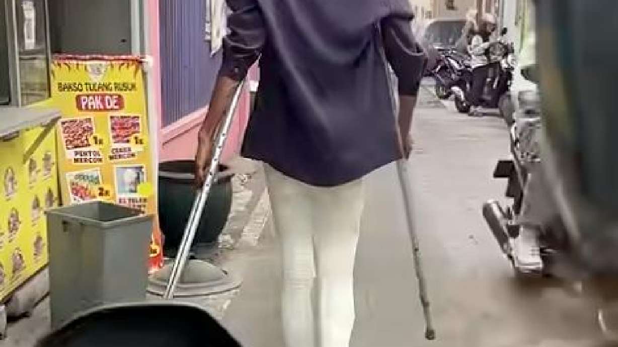 A person walks with crutches Aug. 15 in Malang, Java, Indonesia.