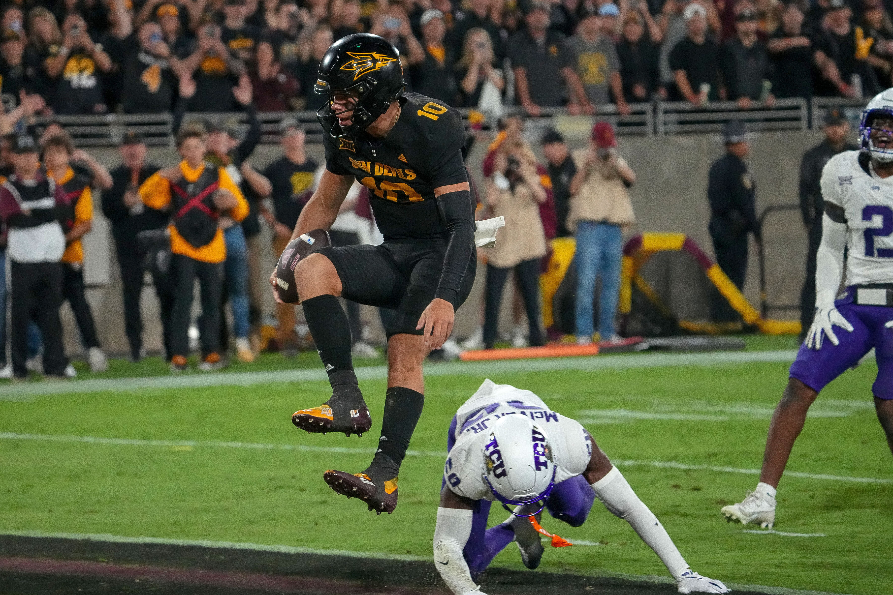 Arizona State Sun Devils quarterback Sam Leavitt (10) scores a touchdown as he jumps over TCU Horned Frogs cornerback Jevon McIver Jr. (20) during the first half of an NCAA college football game Friday, Sept. 26, 2025, in Tempe, Ariz. 