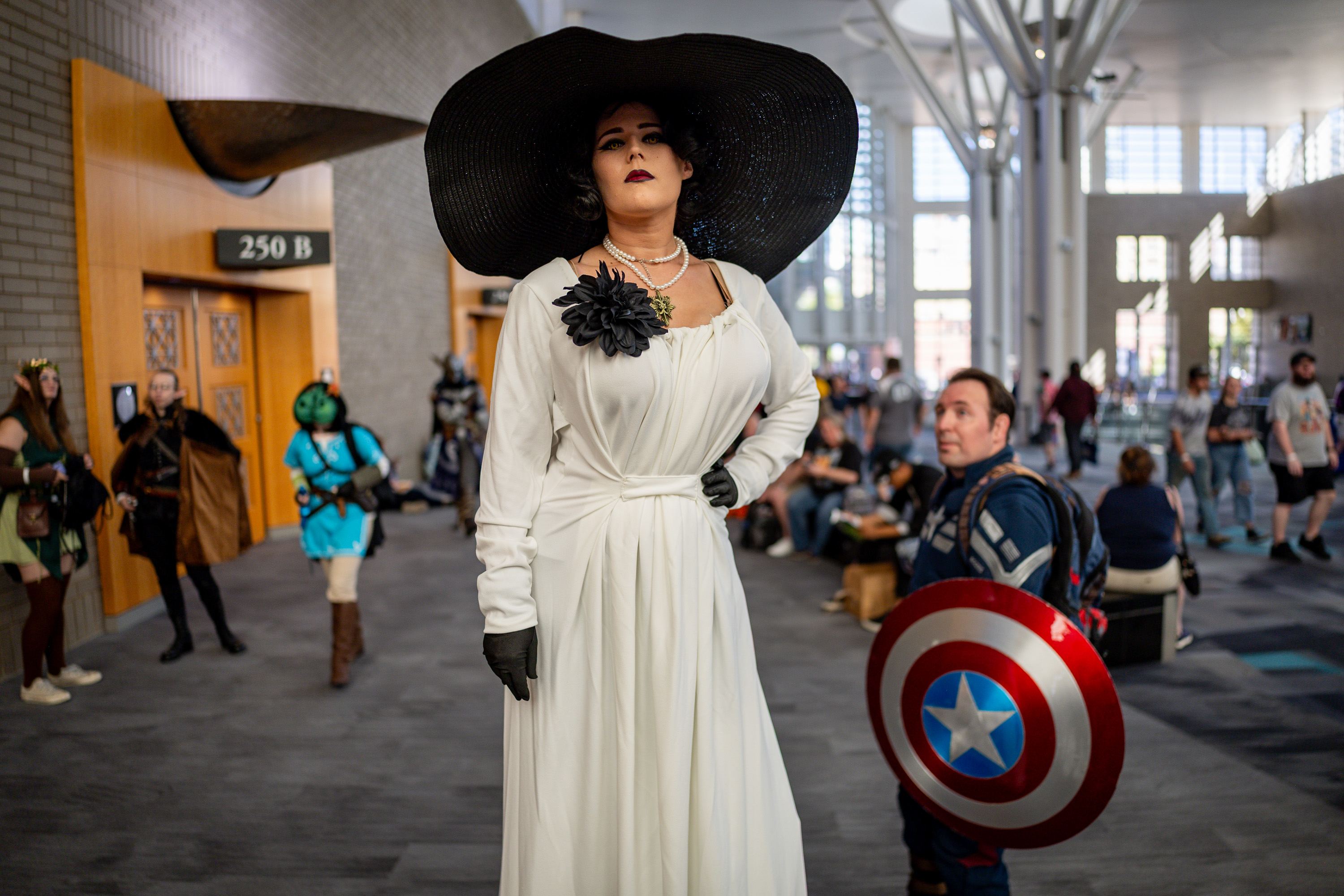 Hayl Daugherty, from Phoenix, dressed as Lady Dimitrescu from "Resident Evil," with her husband dressed as Captain America, at FanX at the Salt Palace Convention Center in Salt Lake City on Thursday. Daugherty, a professional stilter, stands at 7 feet, 5 inches tall.