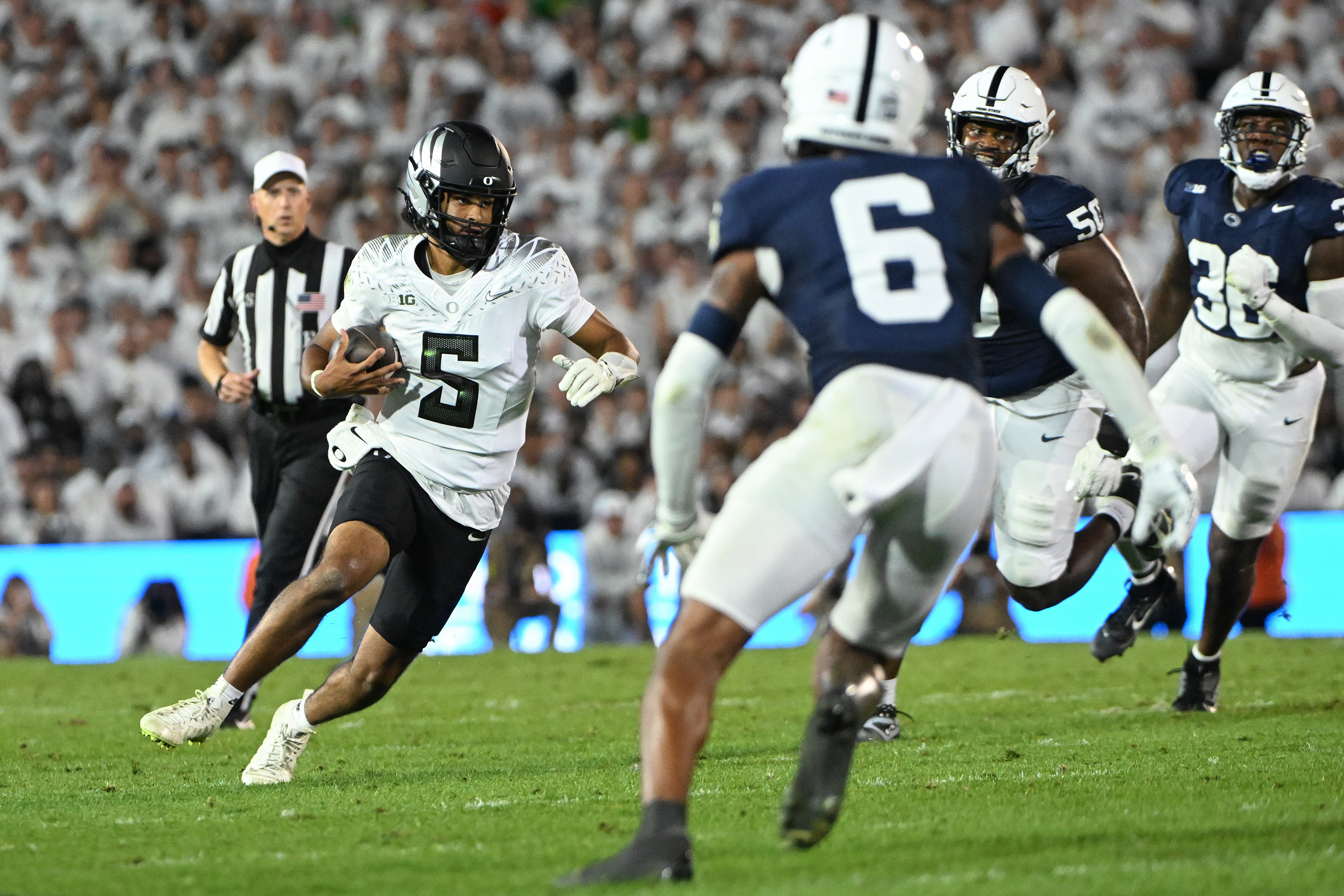 Oregon quarterback Dante Moore (5) looks to elude Penn State safety Zakee Wheatley (6) during the first quarter of an NCAA college football game, Saturday, Sept. 27, 2025, in State College, Pa.