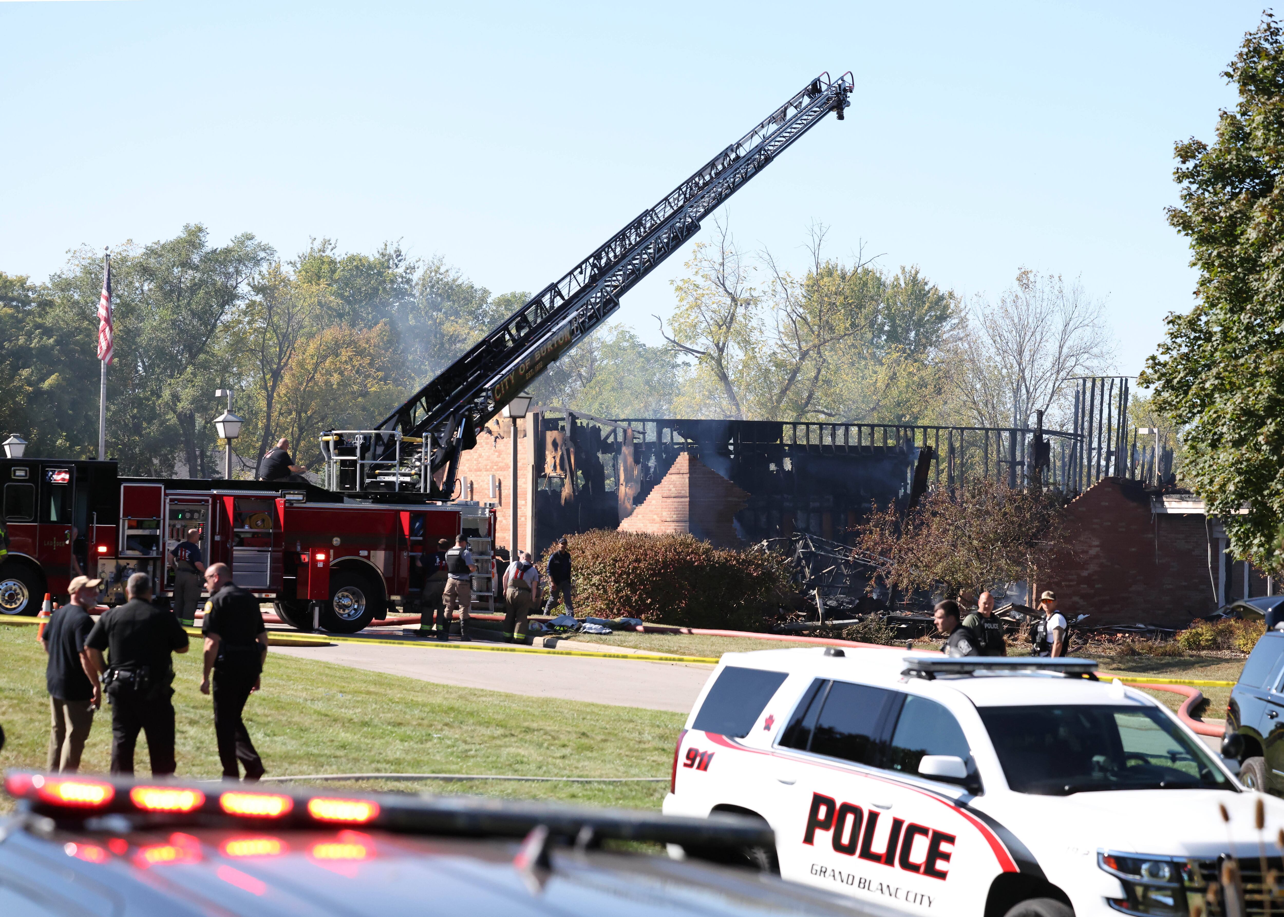 Fire and law enforcement officers stand outside The Church of Jesus Christ of Latter-day Saints meetinghouse, Sunday, in Grand Blanc Township, Mich.