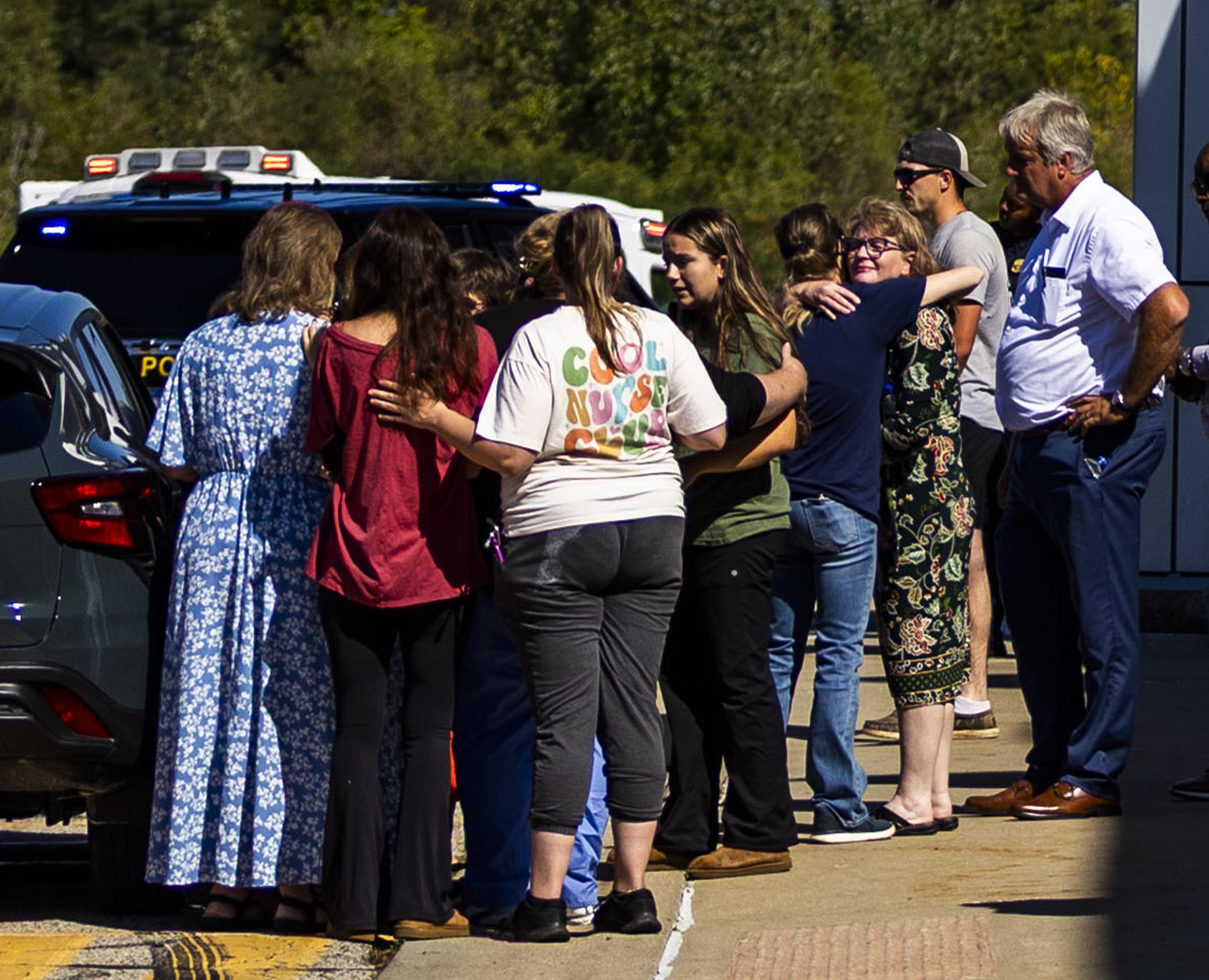 Family and friends wait outside of a movie theater to be reunited with family members after a shooting and fire at a meetinghouse of The Church of Jesus Christ of Latter-day Saints in Grand Blanc Township, Mich., on Sunday.