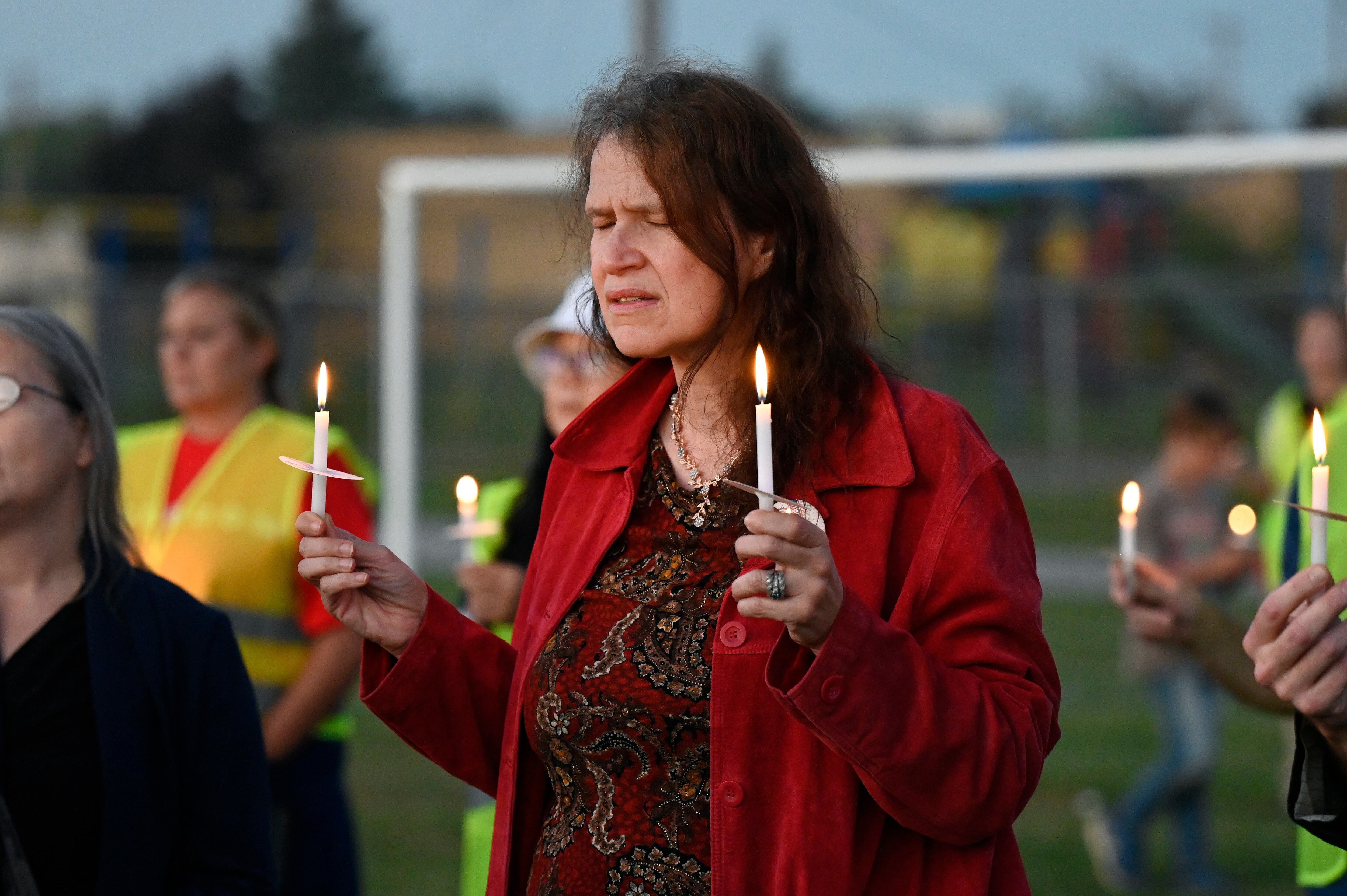 Attendees hold their lit candles during a vigil for a nearby church shooting held at Holy Redeemer Church in Burton, Mich., Sunday.