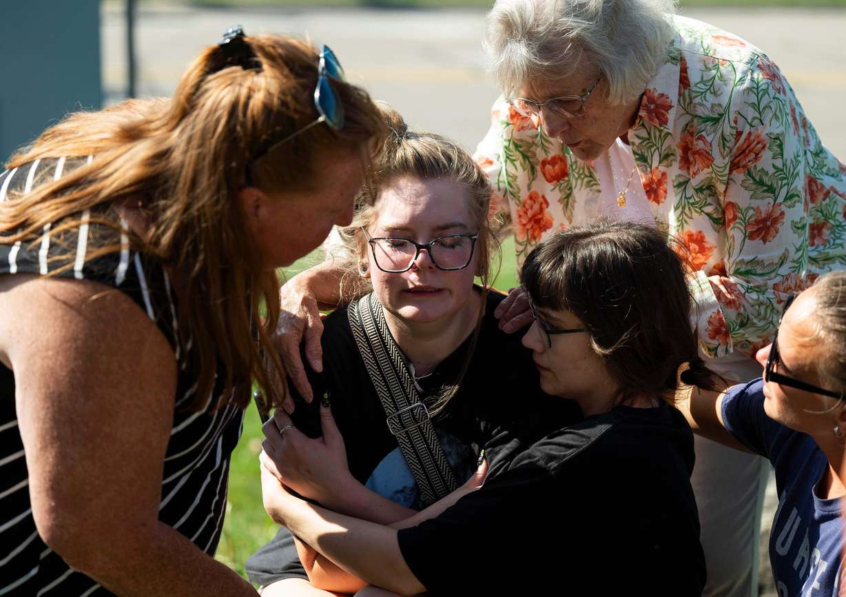 Joanne Green of Fenton, 75, top right, and McKenna Harrington of Davison, 25, second from right, comfort Katelyn Kruse of Fenton, 26, center, after Kruse was present at the scene of a shooting and structure fire at The Church of Jesus Christ of Latter-day Saints on McCandlish Road in Grand Blanc, Mich., Sunday.
