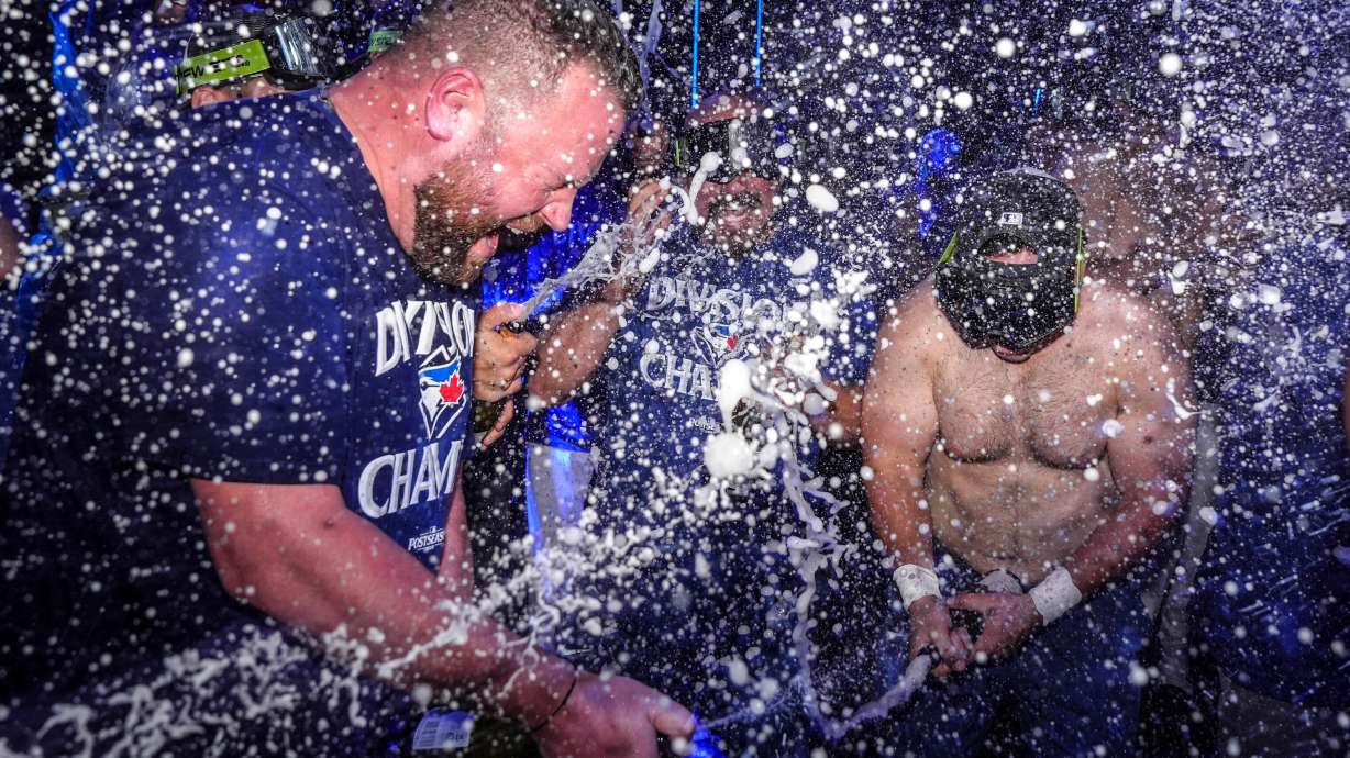 Toronto Blue Jays manager John Schneider, left, joins in with the team to celebrate after winning the American League East Division title following MLB baseball action against the Tampa Bay Rays, in Toronto, Sunday, Sept. 28, 2025.