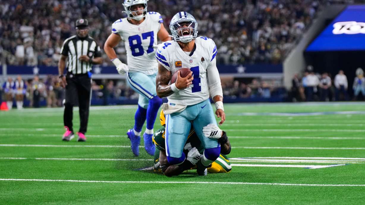 Dallas Cowboys quarterback Dak Prescott (4) is stopped as he carries the ball by Green Bay Packers defensive end Micah Parsons, rear, in overtime of an NFL football game Sunday, Sept. 28, 2025, in Arlington, Texas.