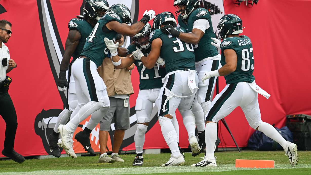 Philadelphia Eagles teammates surround safety Sydney Brown (21) as they celebrate his touchdown during the first half of an NFL football game against the Tampa Bay Buccaneers, Sunday, Sept. 28, 2025, in Tampa, Fla.