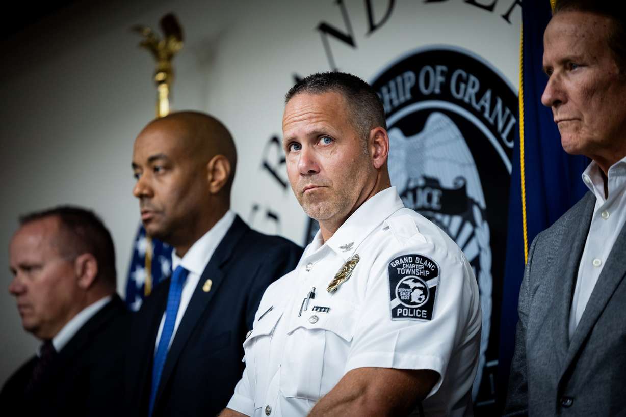 Grand Blanc Township Police Chief William Renye, center, attends a press conference at the police station in Grand Blanc Township, Mich., on Monday, following a shooting and fire at a meetinghouse of The Church of Jesus Christ of Latter-days Saints in Grand Blanc Township on Sunday.