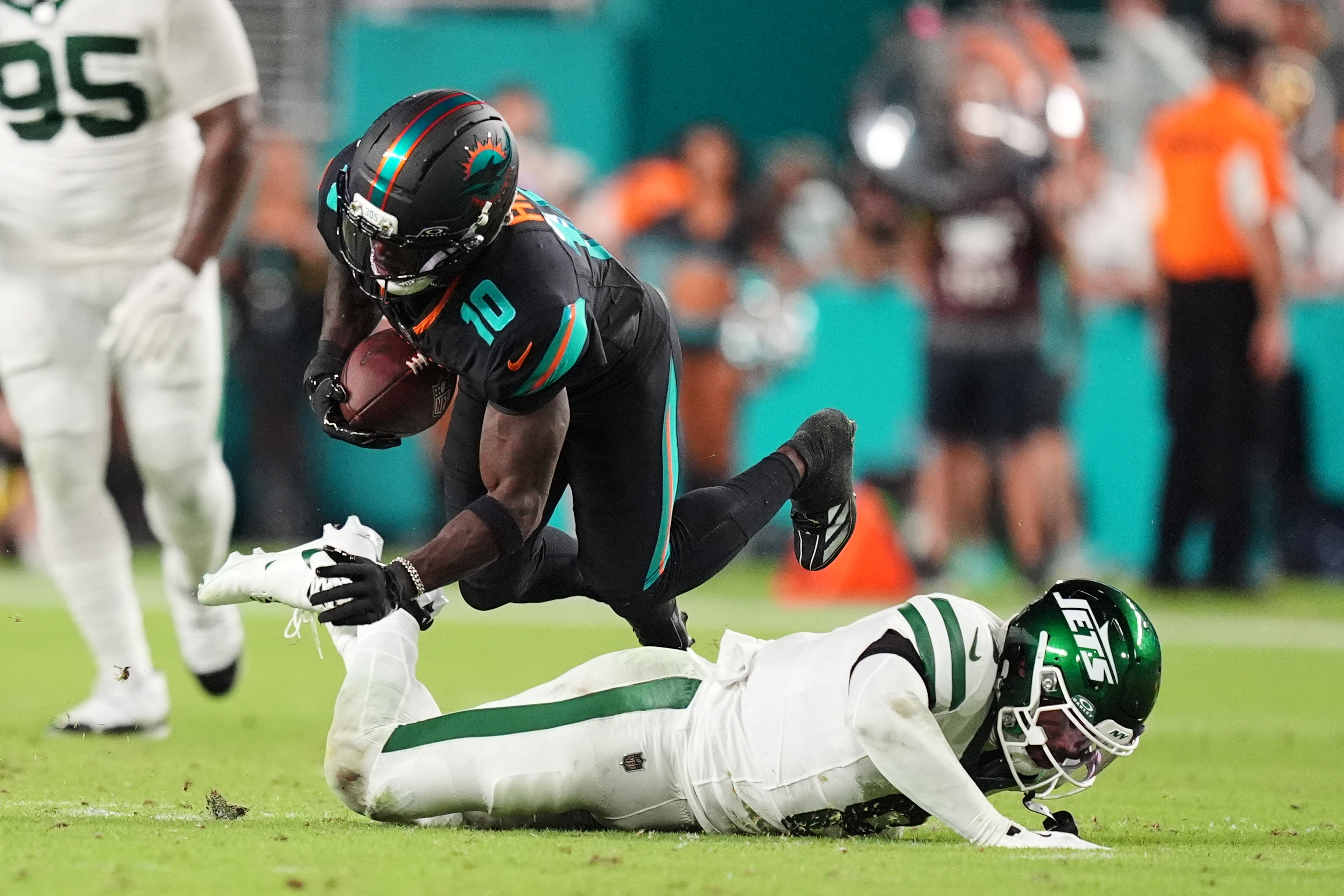 Miami Dolphins wide receiver Tyreek Hill (10) dives forward over a tackle attempt by New York Jets safety Andre Cisco (8) in the first half of an NFL football game, Monday, Sept. 29, 2025, in Miami Gardens, Fla. 