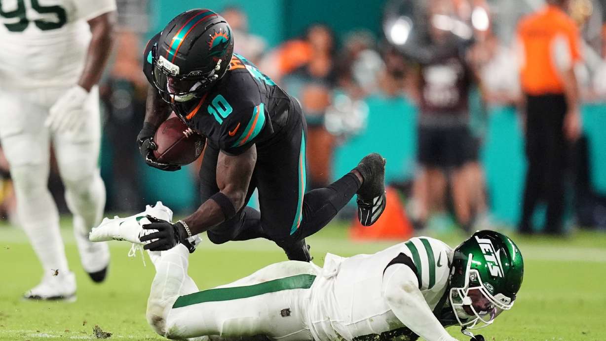 Miami Dolphins wide receiver Tyreek Hill (10) dives forward over a tackle attempt by New York Jets safety Andre Cisco (8) in the first half of an NFL football game, Monday, Sept. 29, 2025, in Miami Gardens, Fla.