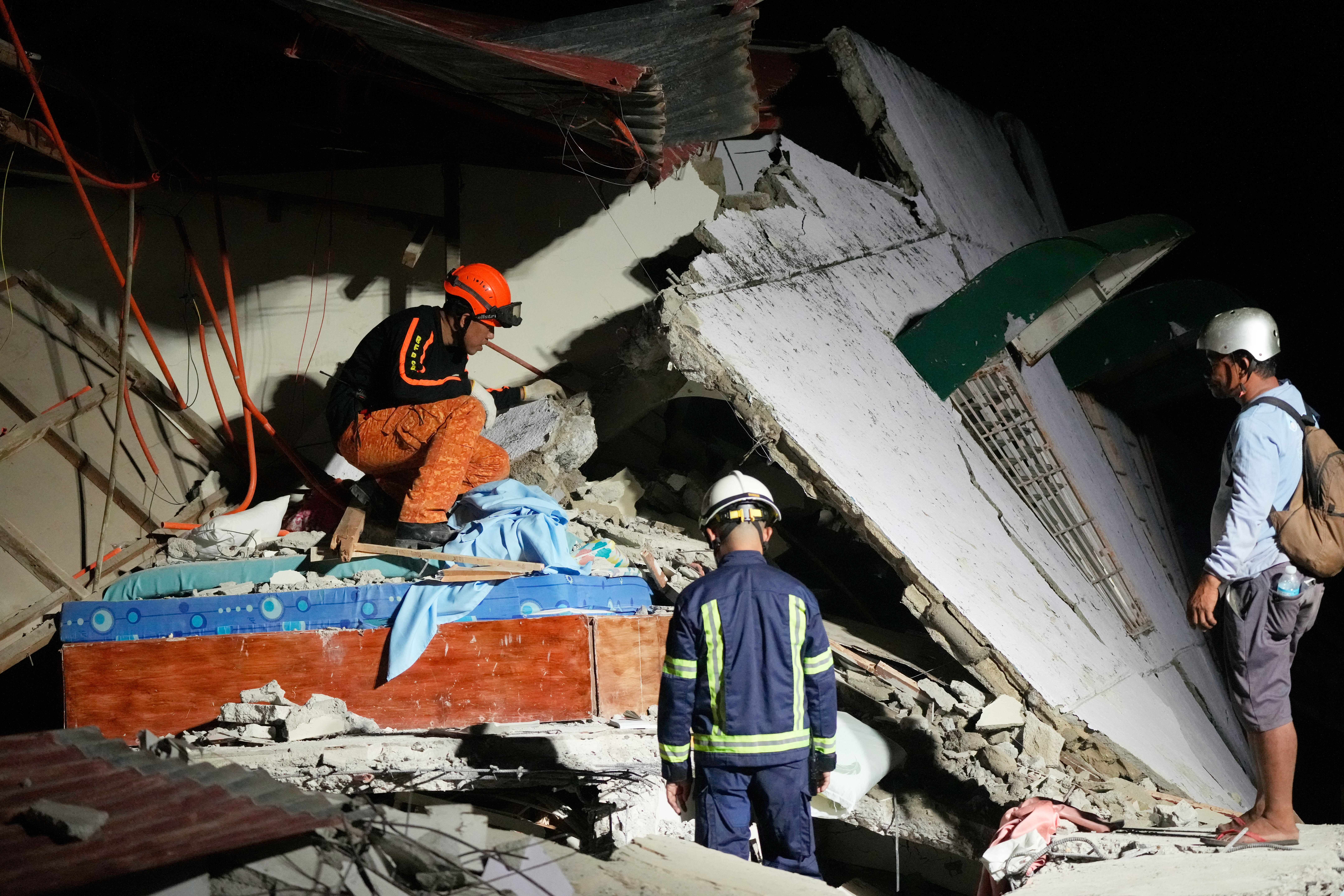 Rescuers check for survivors from the ruins of a collapsed building, Wednesday, after a strong earthquake struck Bogo in the Philippines. At least 72 people have been confirmed dead, and 200 more have been injured.