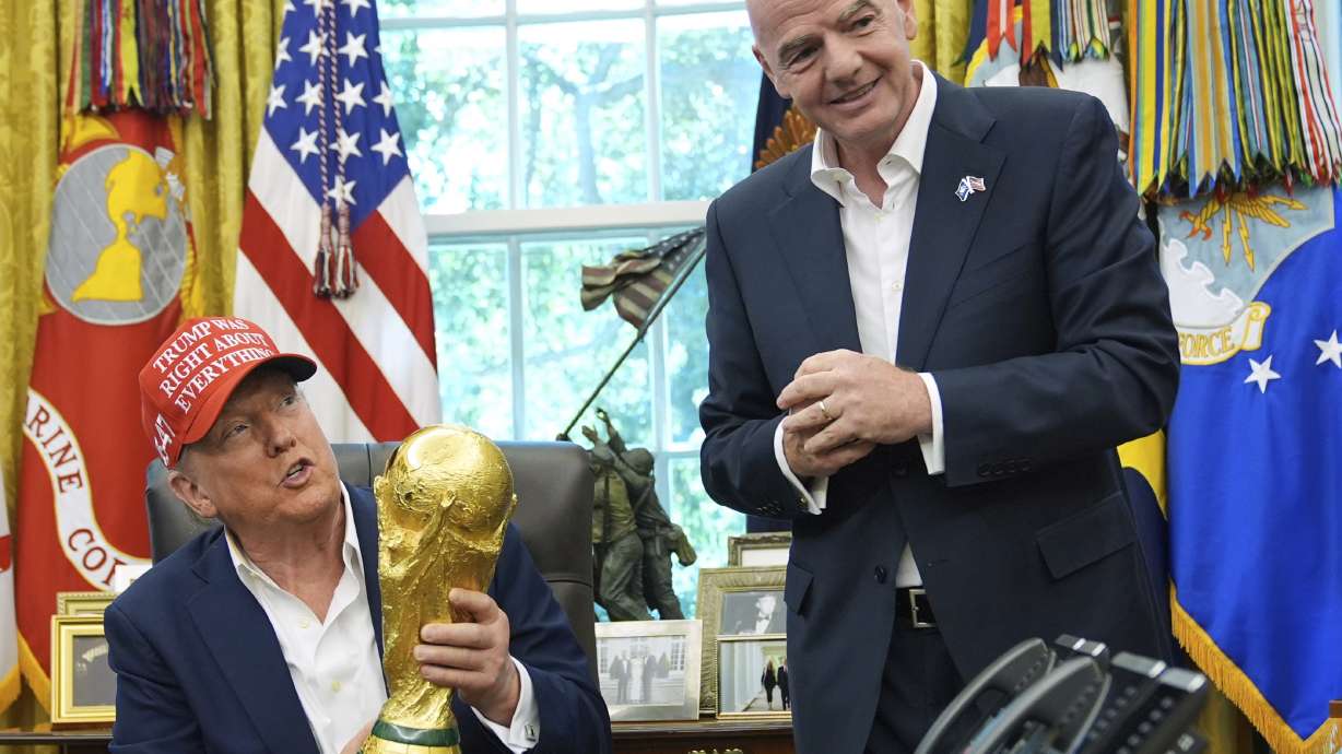 FILE - President Donald Trump holds the FIFA World Cup Winners Trophy as FIFA President Gianni Infantino looks on during an announcement in the Oval Office of the White House, Aug. 22, 2025, in Washington.