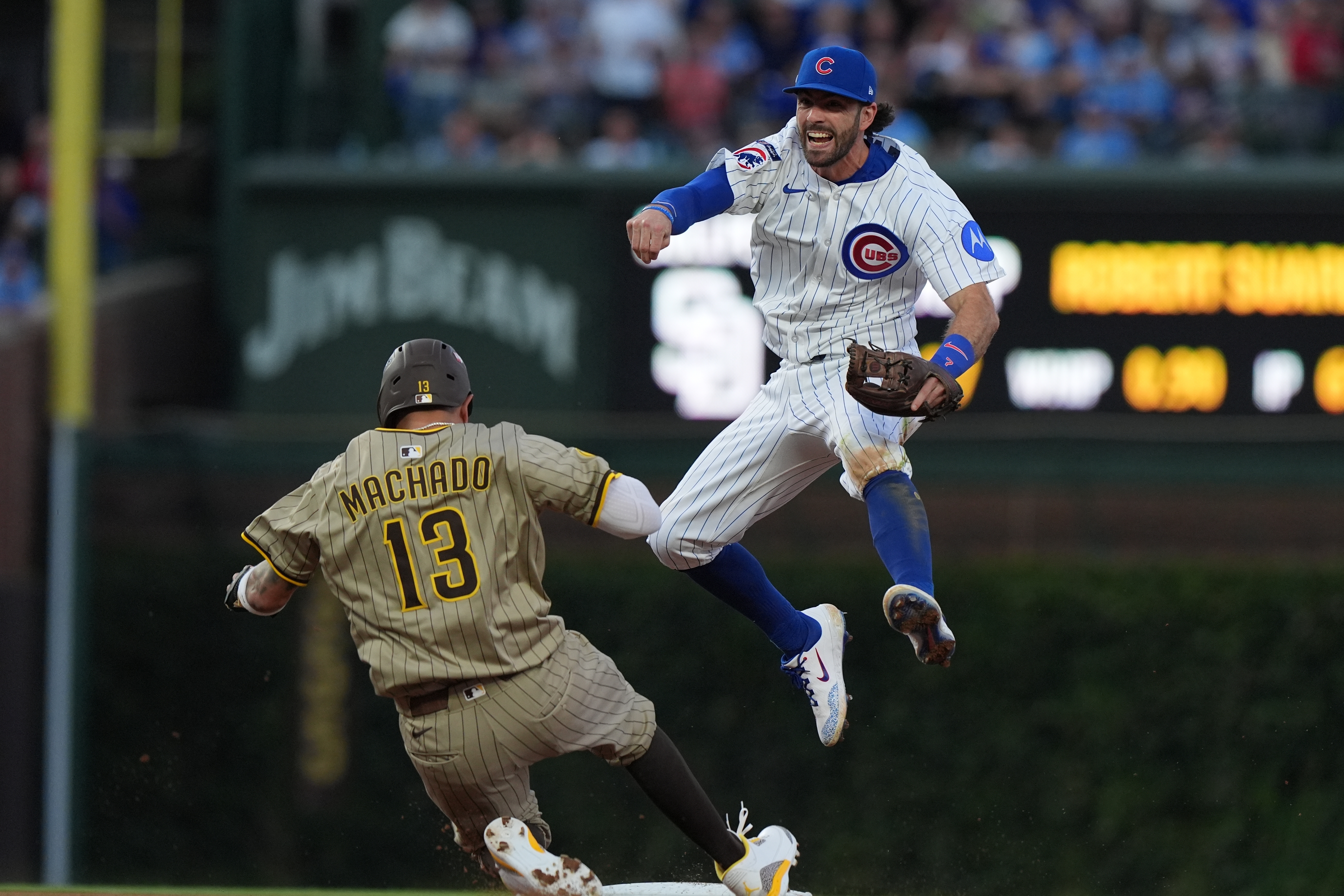 Chicago Cubs' Dansby Swanson leaps over San Diego Padres' Manny Machado to make a play on a ball hit by Jackson Merrill during the sixth inning of Game 3 of a National League wild card baseball game Thursday, Oct. 2, 2025, in Chicago. 