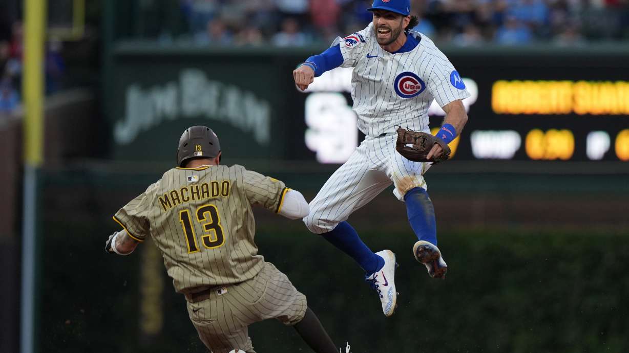 Chicago Cubs' Dansby Swanson leaps over San Diego Padres' Manny Machado to make a play on a ball hit by Jackson Merrill during the sixth inning of Game 3 of a National League wild card baseball game Thursday, Oct. 2, 2025, in Chicago.