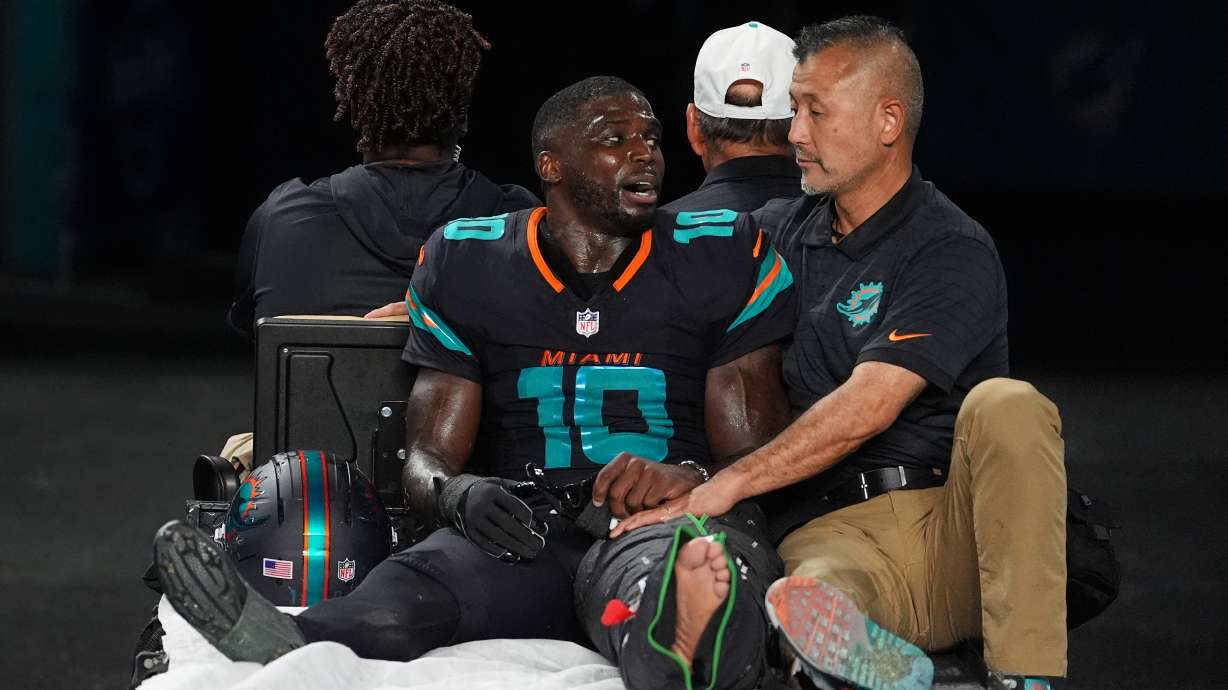 Miami Dolphins wide receiver Tyreek Hill (10) talks with a staff member as he is carted off the field after suffering an unknown lower leg injury in the second half of an NFL football game against the New York Jets, Monday, Sept. 29, 2025, in Miami Gardens, Fla.