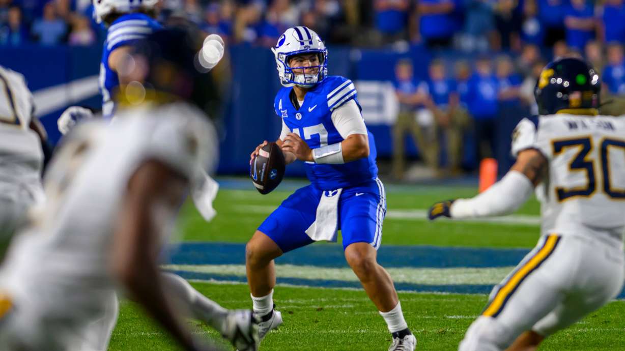BYU quarterback Bear Bachmeier, center, looks to pass the ball during the first half of an NCAA college football game against West Virginia, Friday, Oct. 3, 2025, in Provo, Utah.