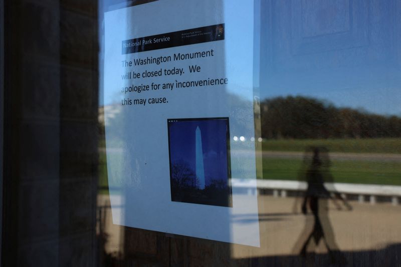 A person walks outside of the Washington Monument as a sign announces it is closed, on the fourth day of a partial government shutdown in Washington, D.C., Saturday. 