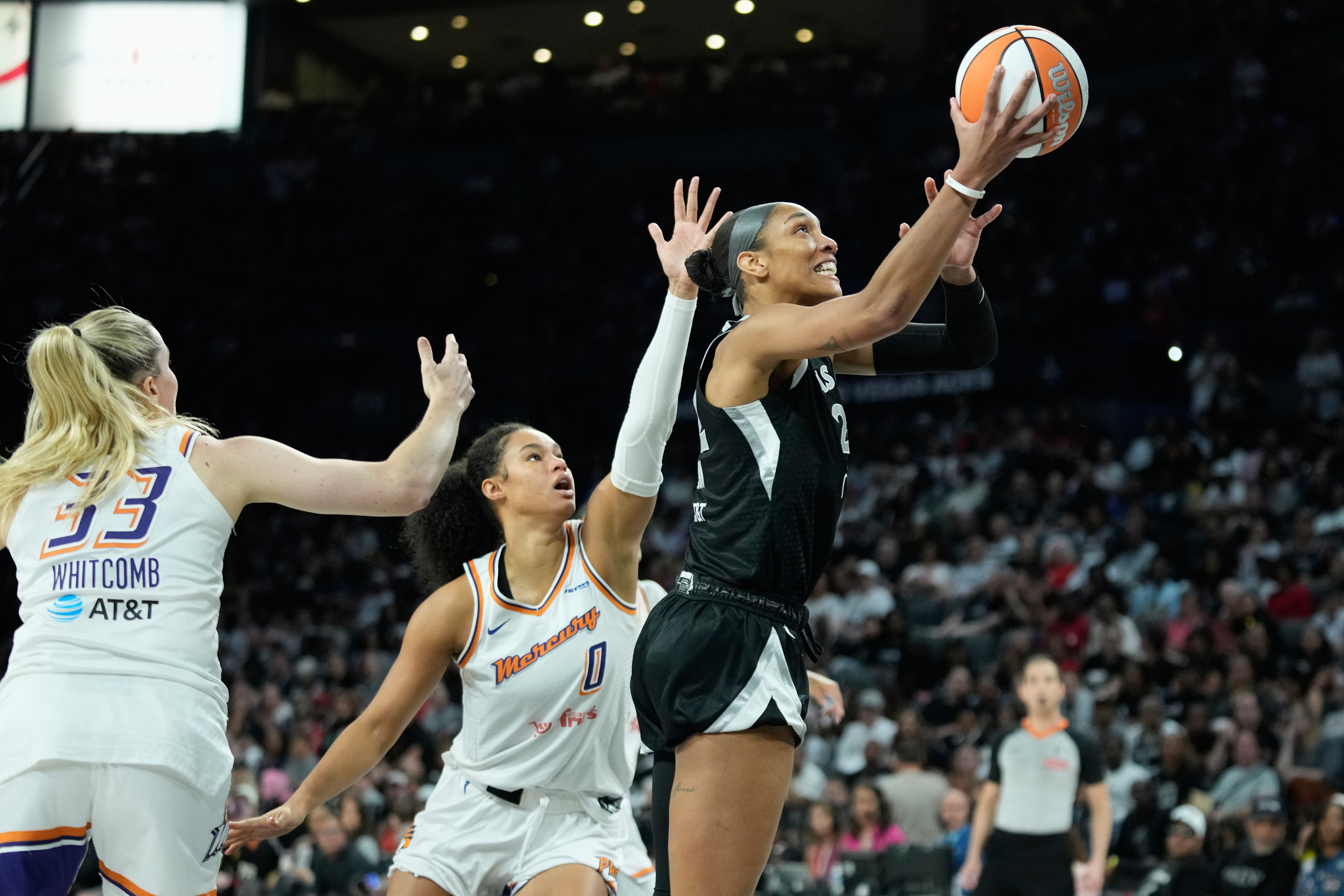 Las Vegas Aces center A'ja Wilson (22) shoots as Phoenix Mercury guard Sami Whitcomb (33) and forward Satou Sabally (0) defend during the second half in Game 2 of the WNBA basketball finals, Sunday, Oct. 5, 2025, in Las Vegas.