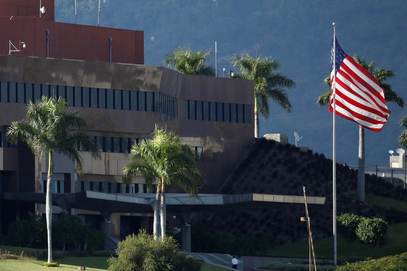 A man walks next to a U.S. flag at the U.S. embassy in Caracas, Venezuela Jan. 24, 2019. Venezuela's president says he warned the U.S. of a possible attack on the U.S. embassy.