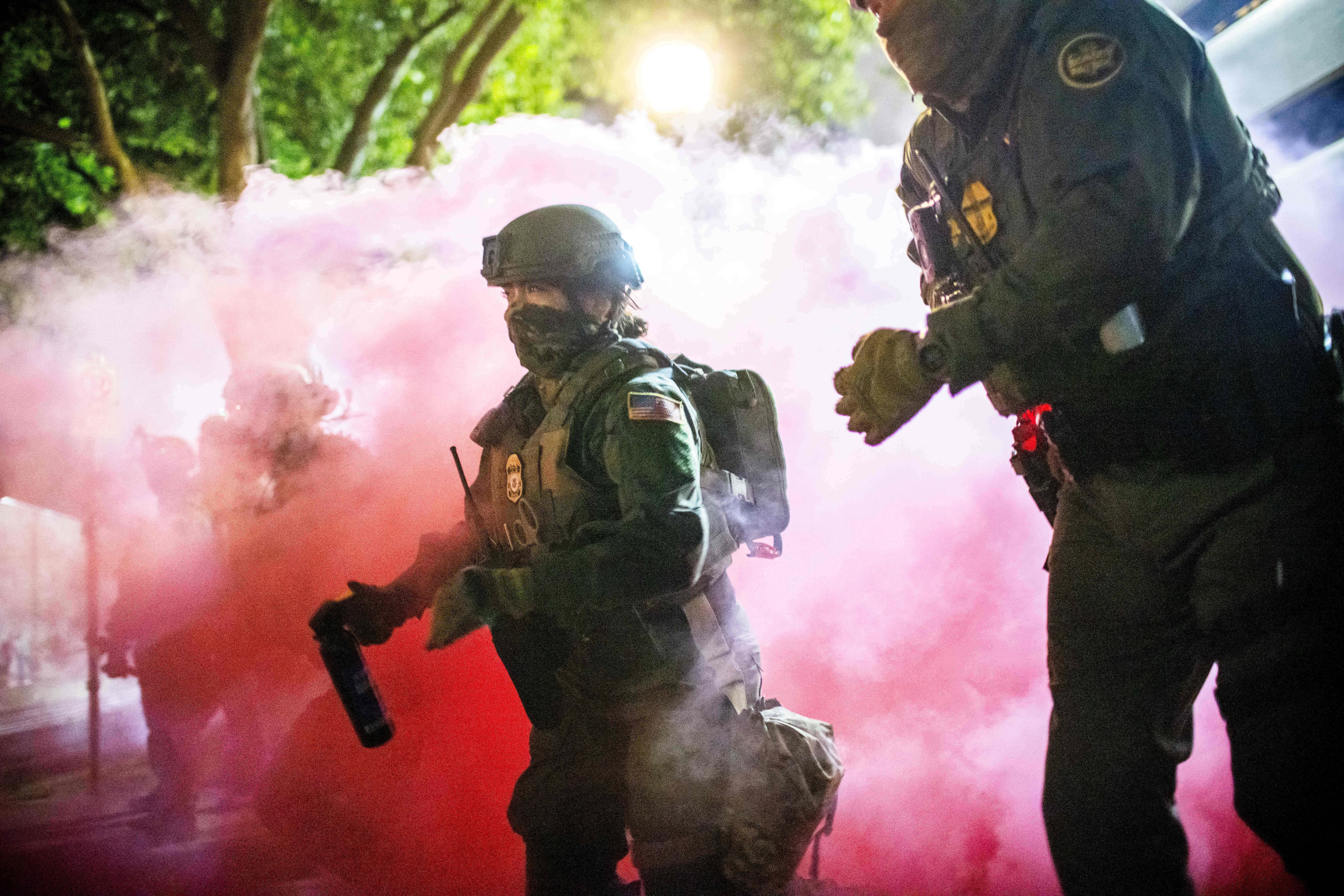 Police and federal officers throw gas canisters to disperse protesters near a U.S. Immigration and Customs Enforcement facility in Portland, Ore., on Sunday.