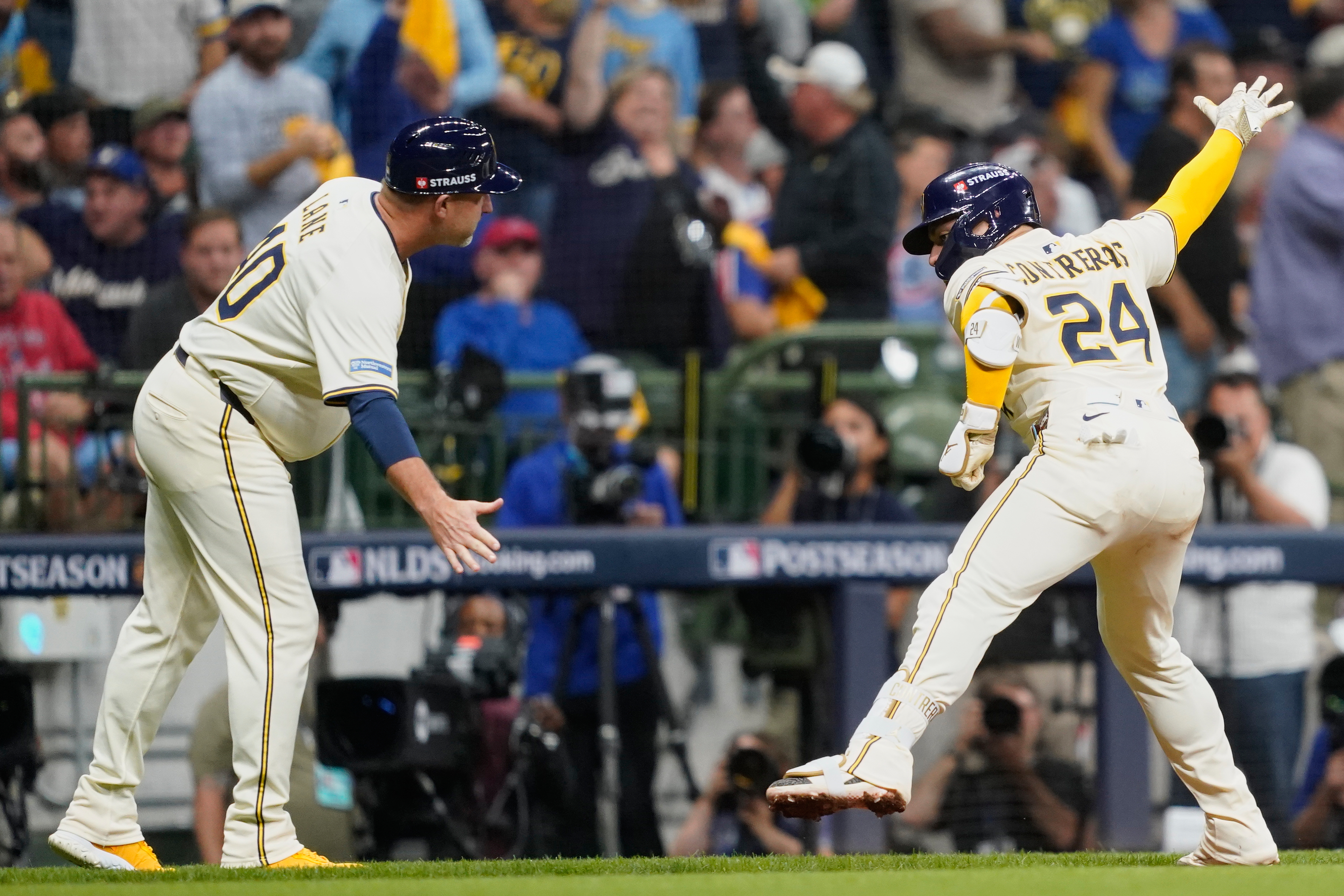 Milwaukee Brewers' William Contreras (24) celebrates with third base coach Jason Lane (40) after hitting a solo home run during the third inning of Game 2 of baseball's National League Division Series against the Chicago Cubs Monday, Oct. 6, 2025, in Milwaukee. 