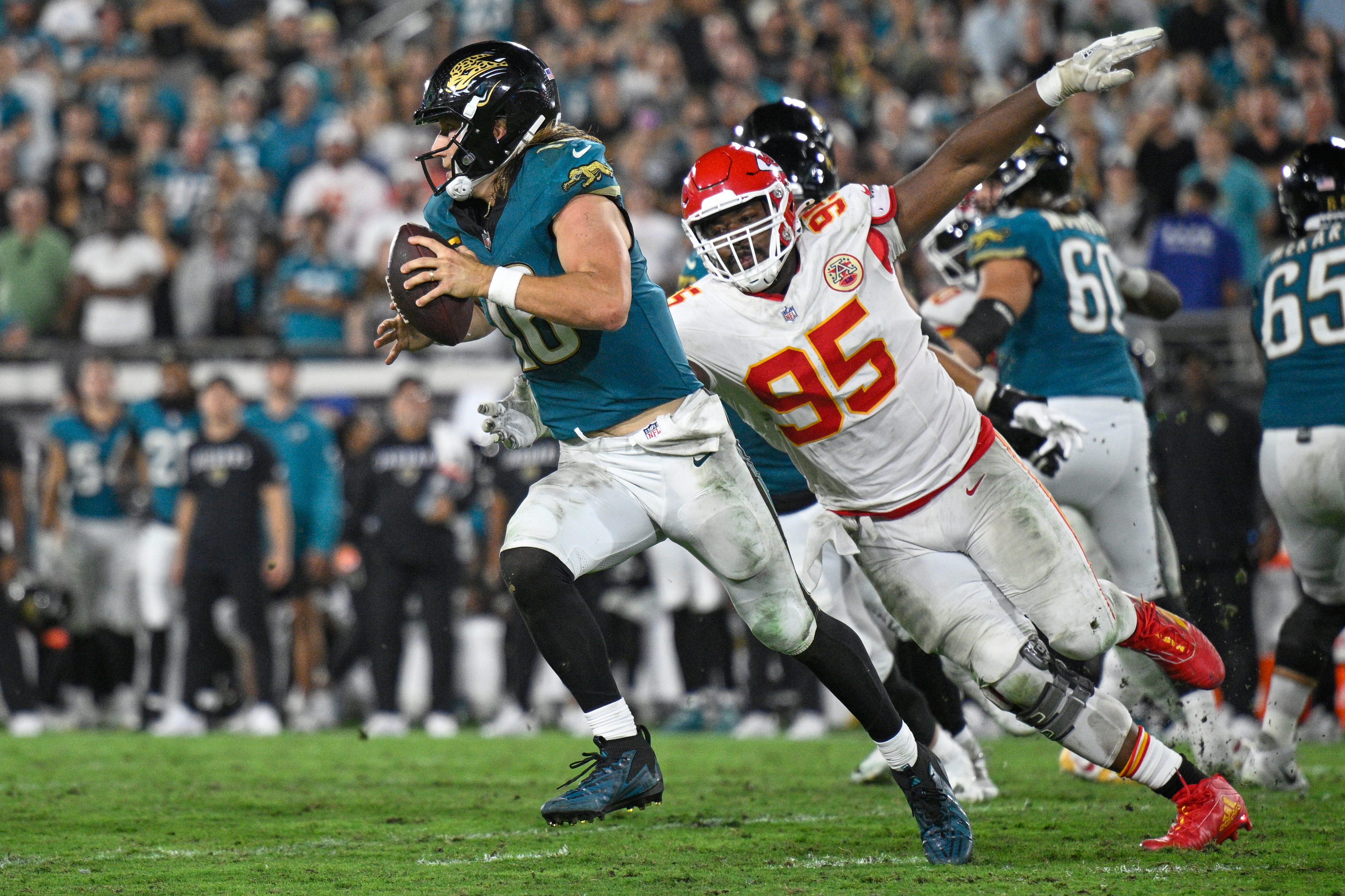 Jacksonville Jaguars quarterback Trevor Lawrence (16) gets past Kansas City Chiefs defensive tackle Chris Jones (95) as he runs the ball during the second half of an NFL football game, Monday, Oct. 6, 2025, in Jacksonville, Fla.