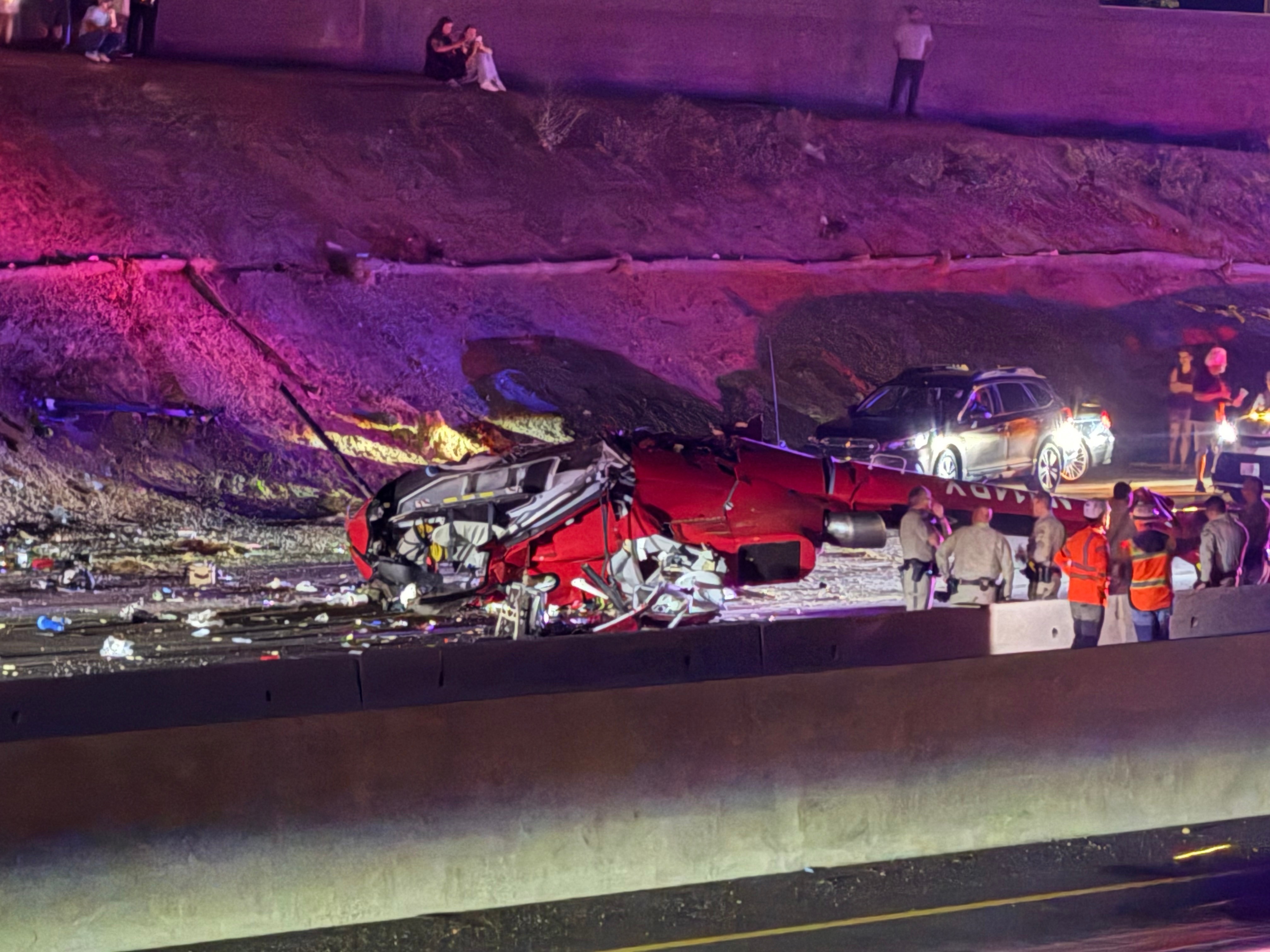 Law enforcement officers stand near the wreckage of a helicopter that crashed on eastbound Highway 50, in Sacramento, Calif., Monday. Three occupants, including the pilot, were taken to the hospital in critical condition following the crash.