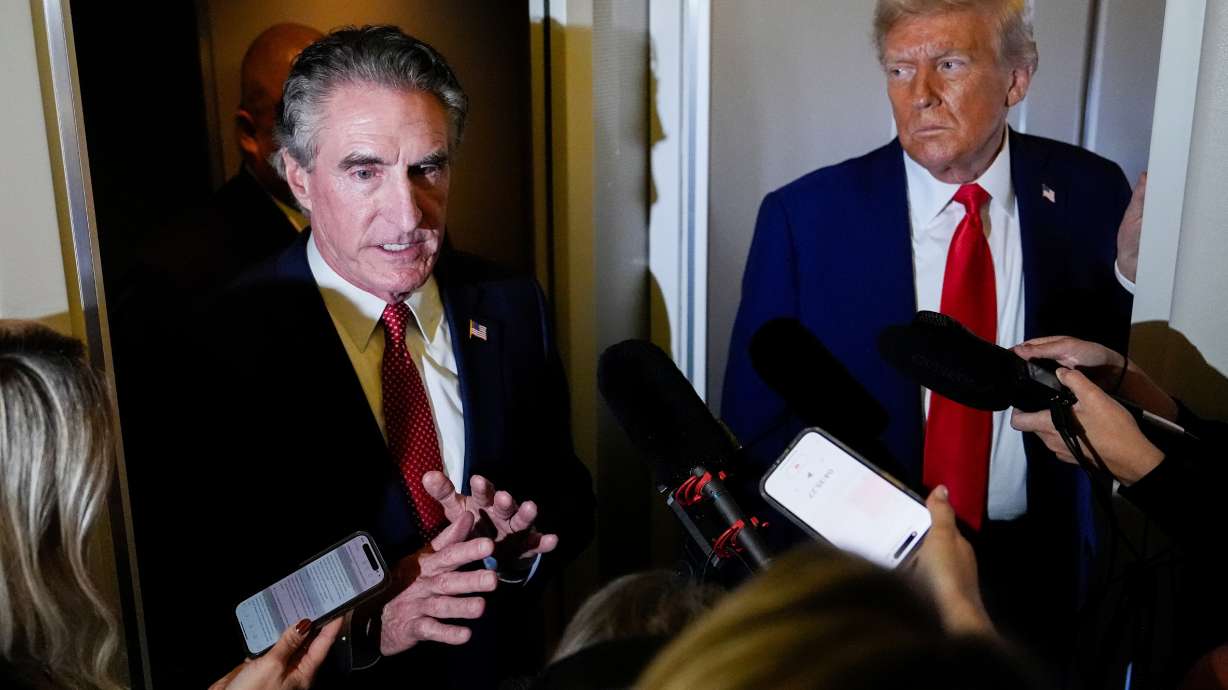President Donald Trump watches as Interior Secretary Doug Burgum speaks to reporters aboard Air Force One while en route to Joint Base Andrews, Md., on Sept. 21.