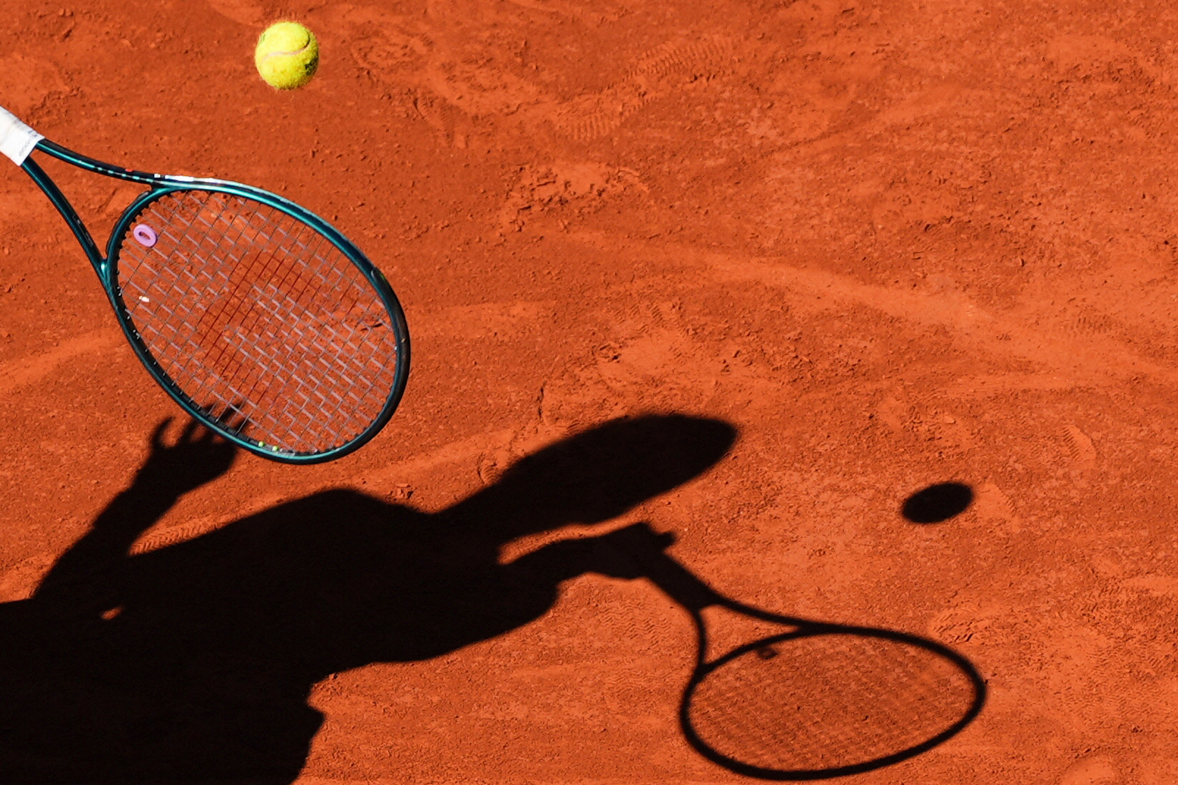 FILE - A player casts a shadow upon the court as they play a shot during the French Tennis Open, Friday, May 30, 2025, at the Roland-Garros stadium in Paris.
