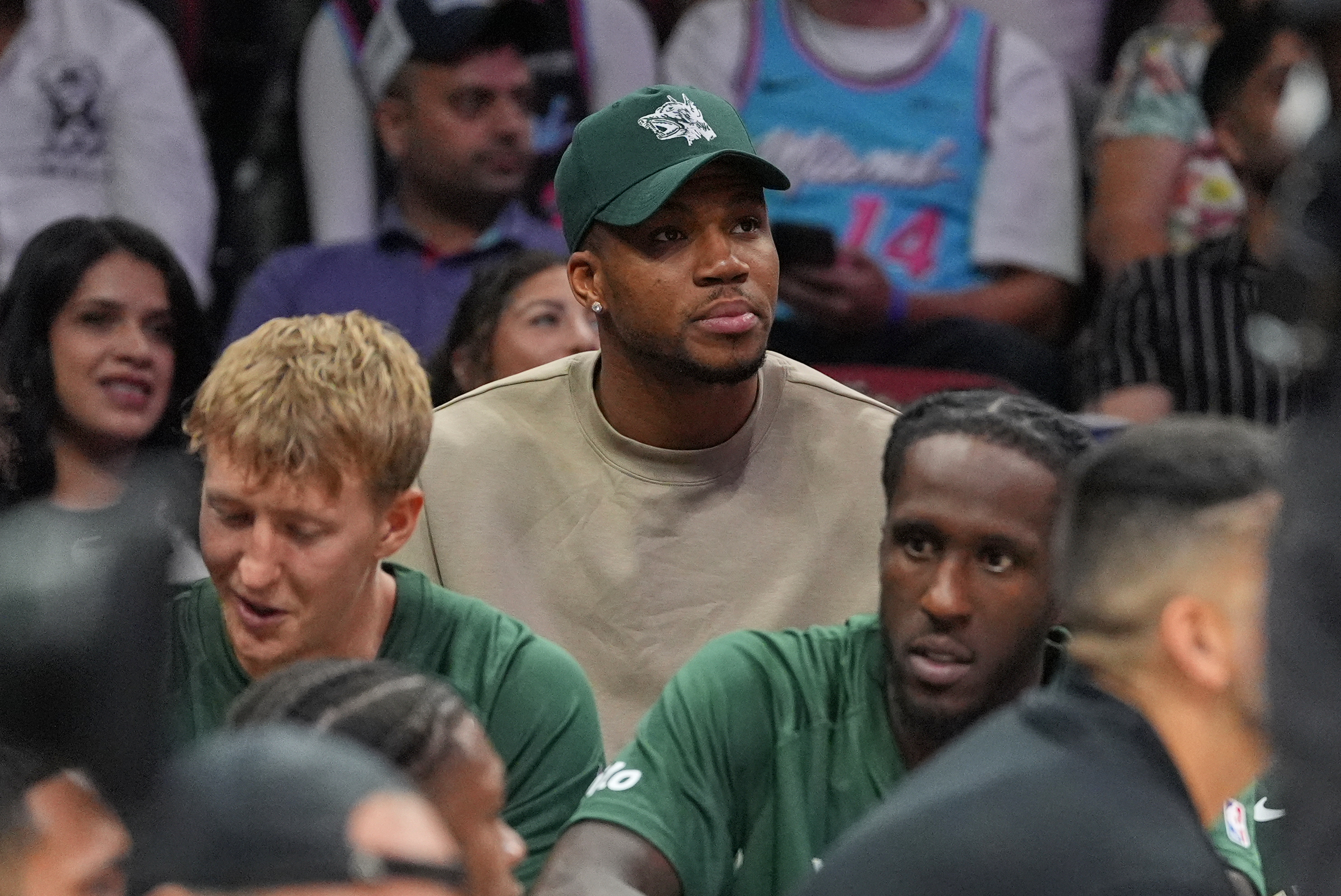 Milwaukee Bucks forward Giannis Antetokounmpo, who is recovering from COVID-19, sits behind his team's bench as he watches the second half of a preseason NBA basketball game against the Miami Heat, Monday, Oct. 6, 2025, in Miami. 