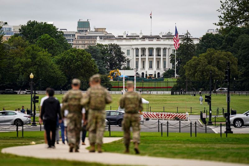 Members of the National Guard walk near the White House in Washington, Aug. 21. A federal judge blocked President Donald Trump from deploying the guard to Chicago on Thursday, saying it would "only add fuel to the fire."