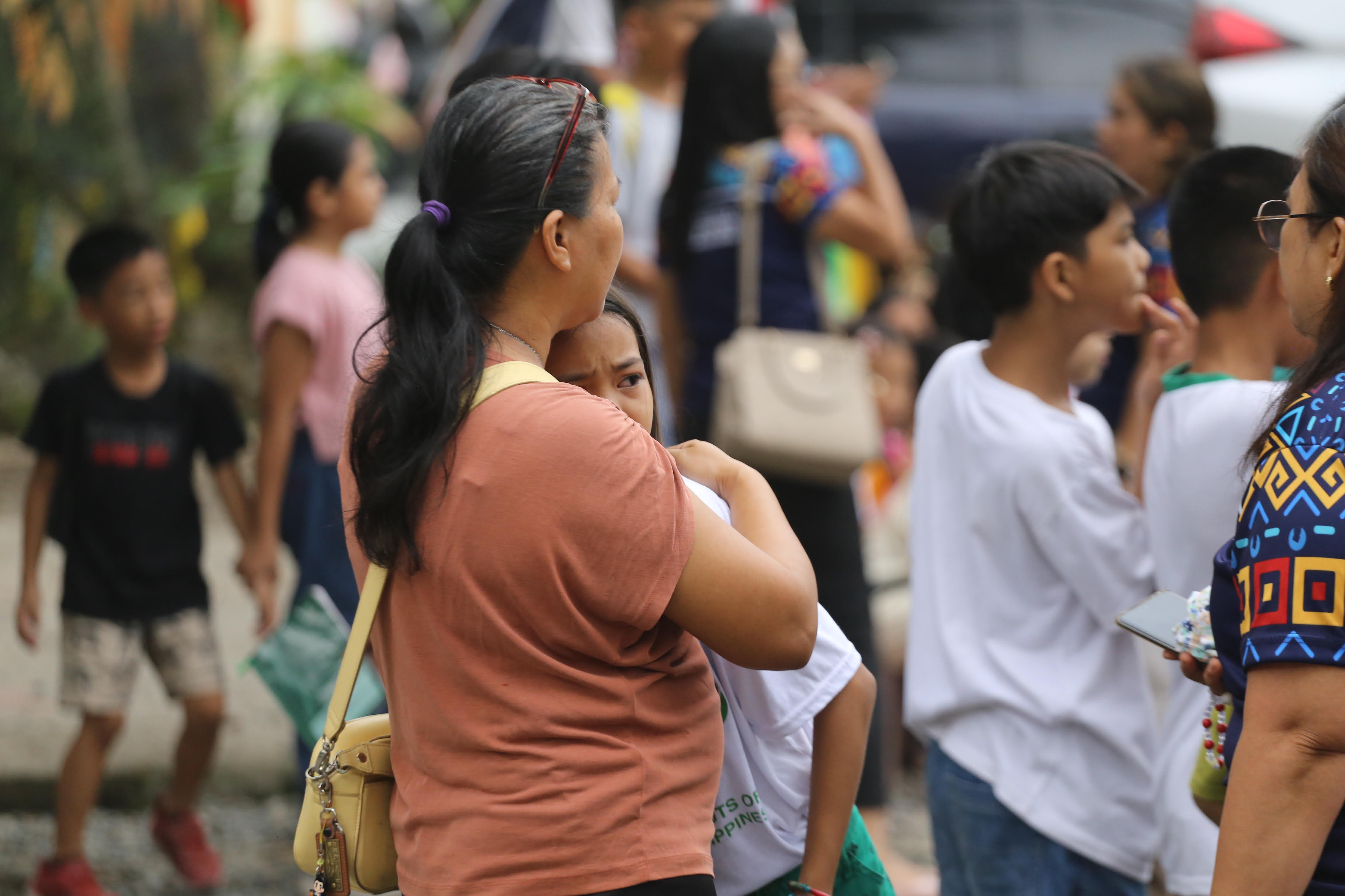A woman hugs a child as parents and children evacuate a school after a strong earthquake in Davao City, Philippines, on Friday.