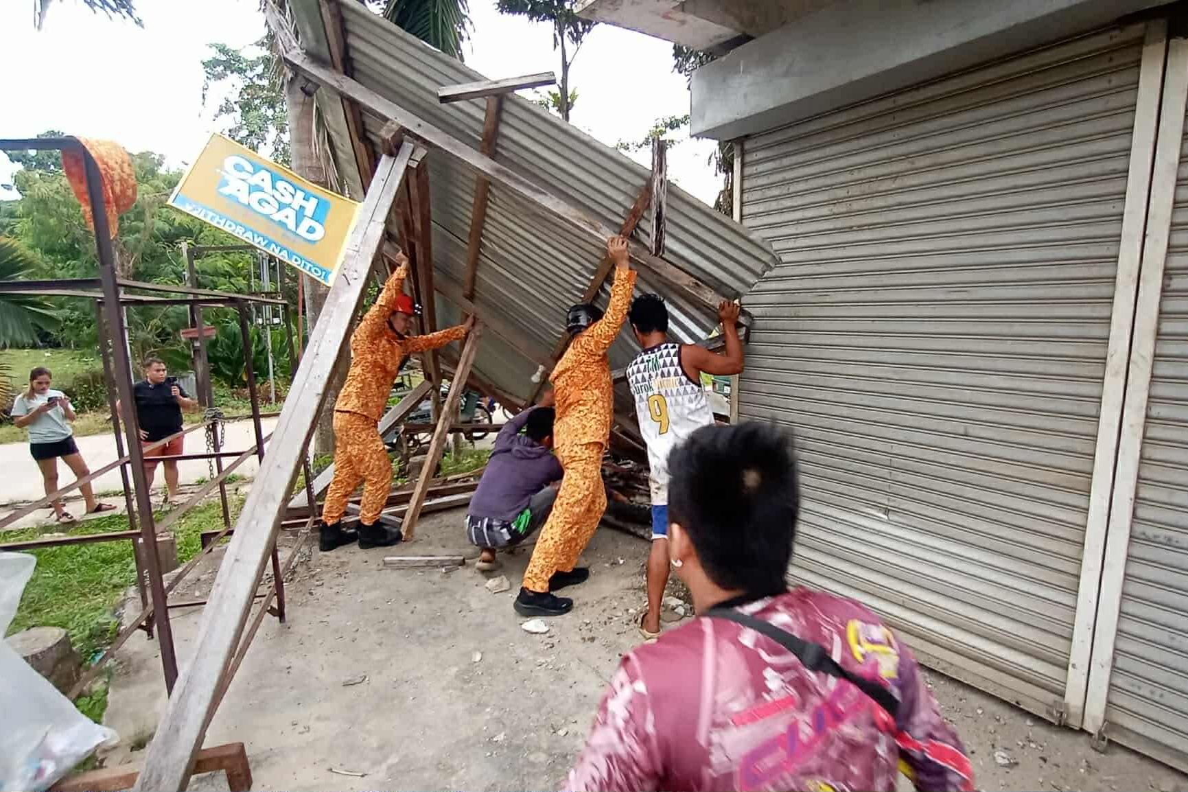 In this photo provided by the Bureau of Fire Protection, firefighters and residents hold on a toppled structure following a strong earthquake in Davao Oriental province, southern Philippines on Friday.