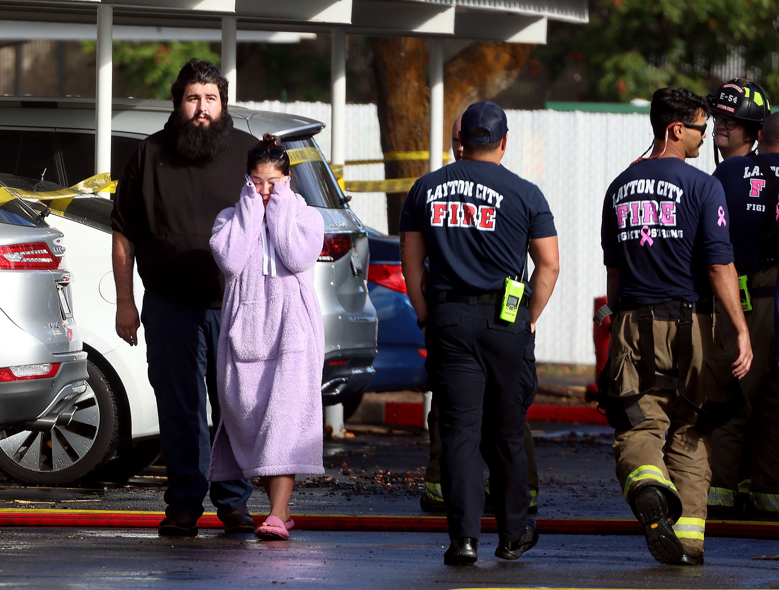 Residents of Layton Meadows Apartments walk past firefighters after a fire impacted 24 units on Friday.
